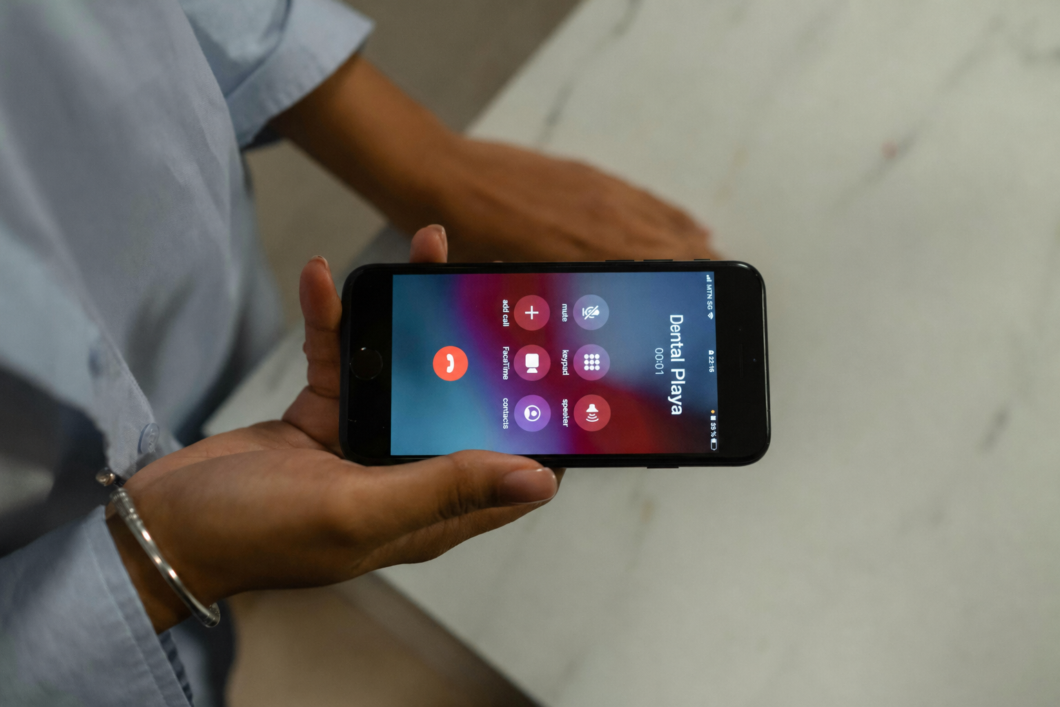 Person holding a smartphone with an ongoing call to 'Dental Playa'.