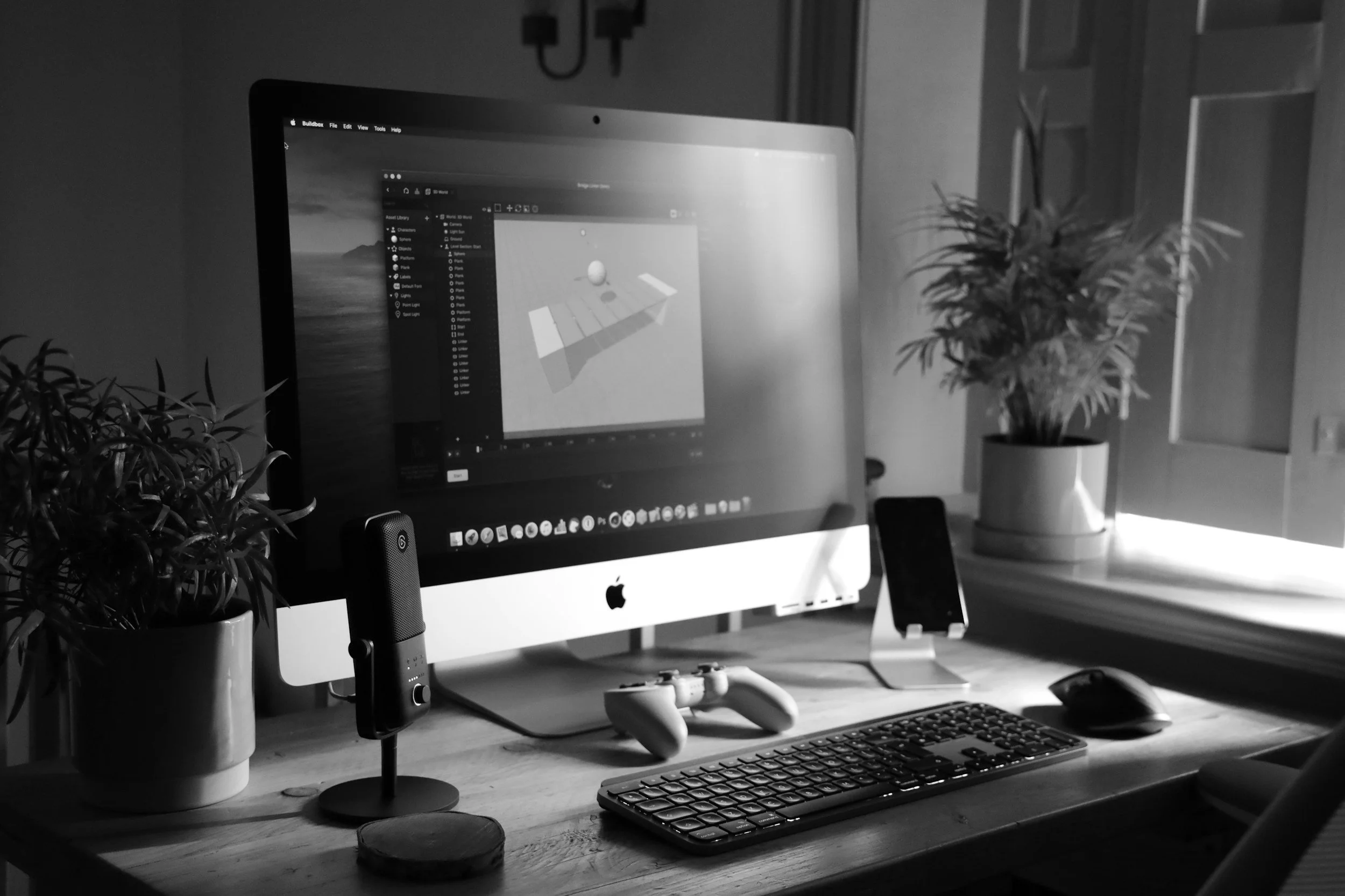 A black and white photo of a computer workspace featuring an Apple iMac, accompanied by a keyboard and mouse.