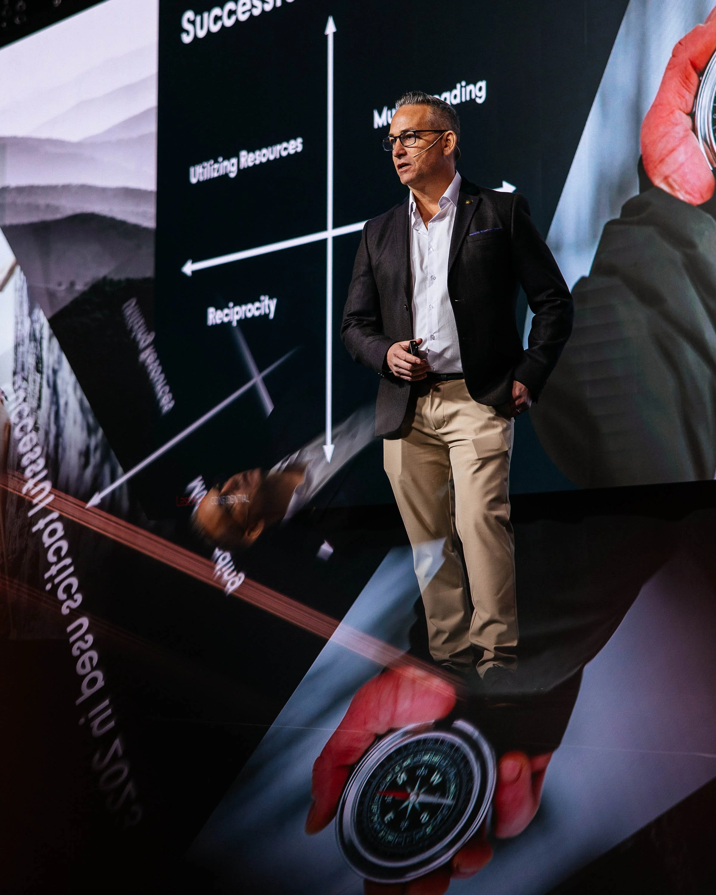 A man giving a presentation with a large screen displaying a graph with labeled axes, titled 'Success'.