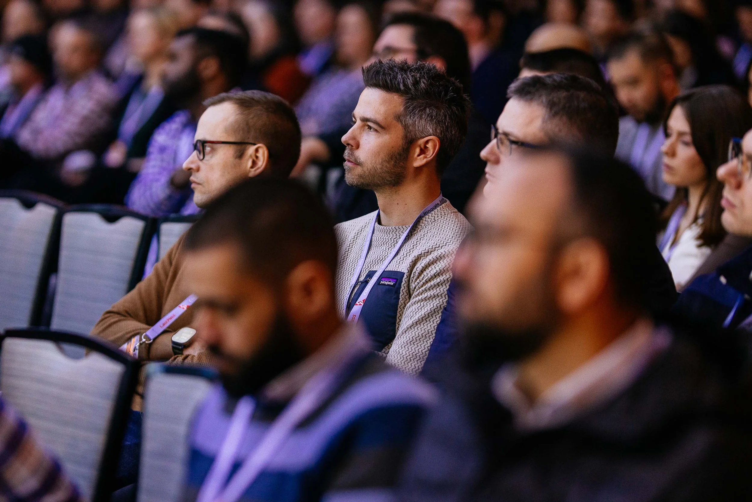 Attendees at a conference sitting and listening intently.