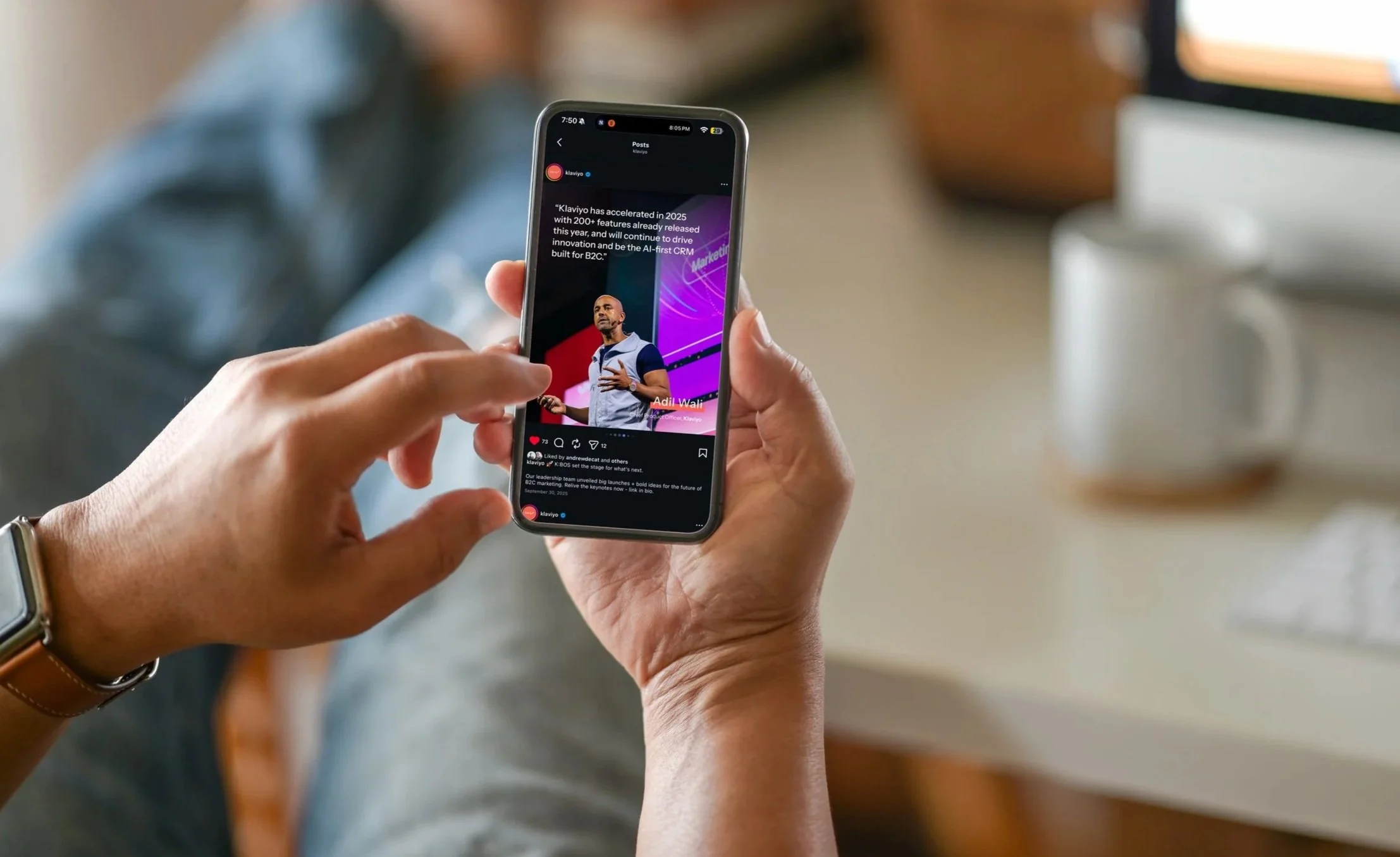 Person holding a smartphone displaying a social media post about Klaviyo's 2025 features, with a man giving a presentation on stage in the post.