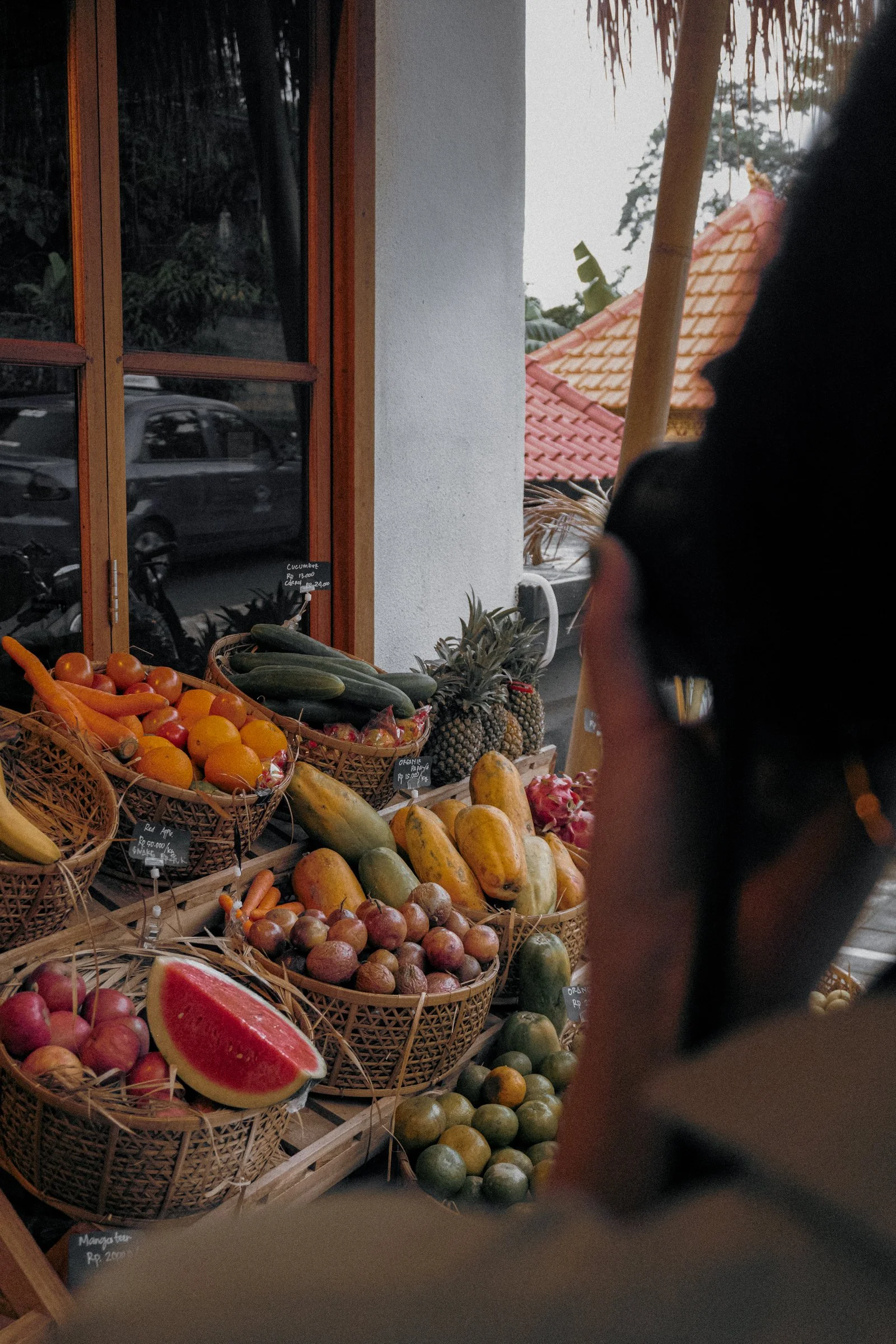 Woman selecting fruit at a local market stand with seasonal produce — a detail from a small‑group women’s travel retreat.