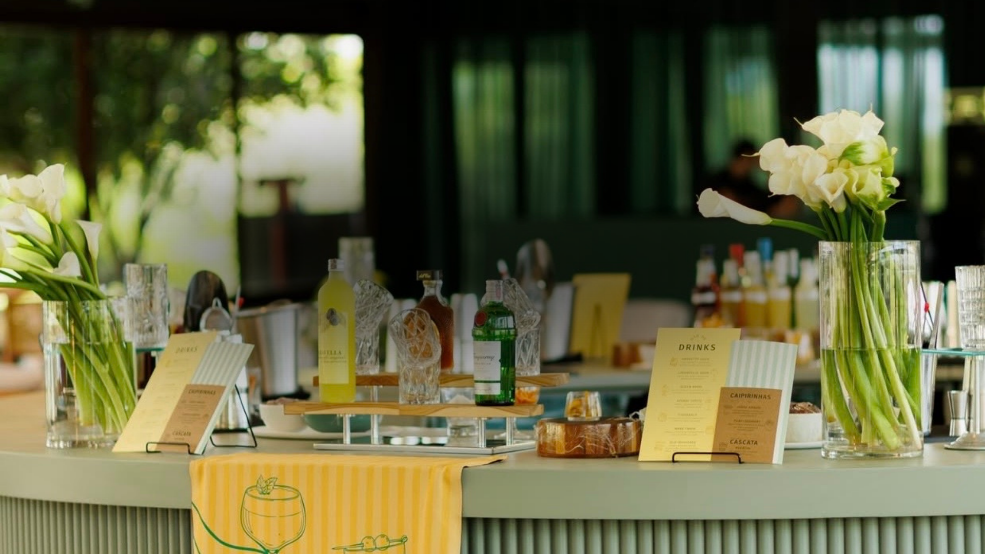 Mesa decorada com vasos de flores brancas e cartas de menu em um ambiente com iluminação natural