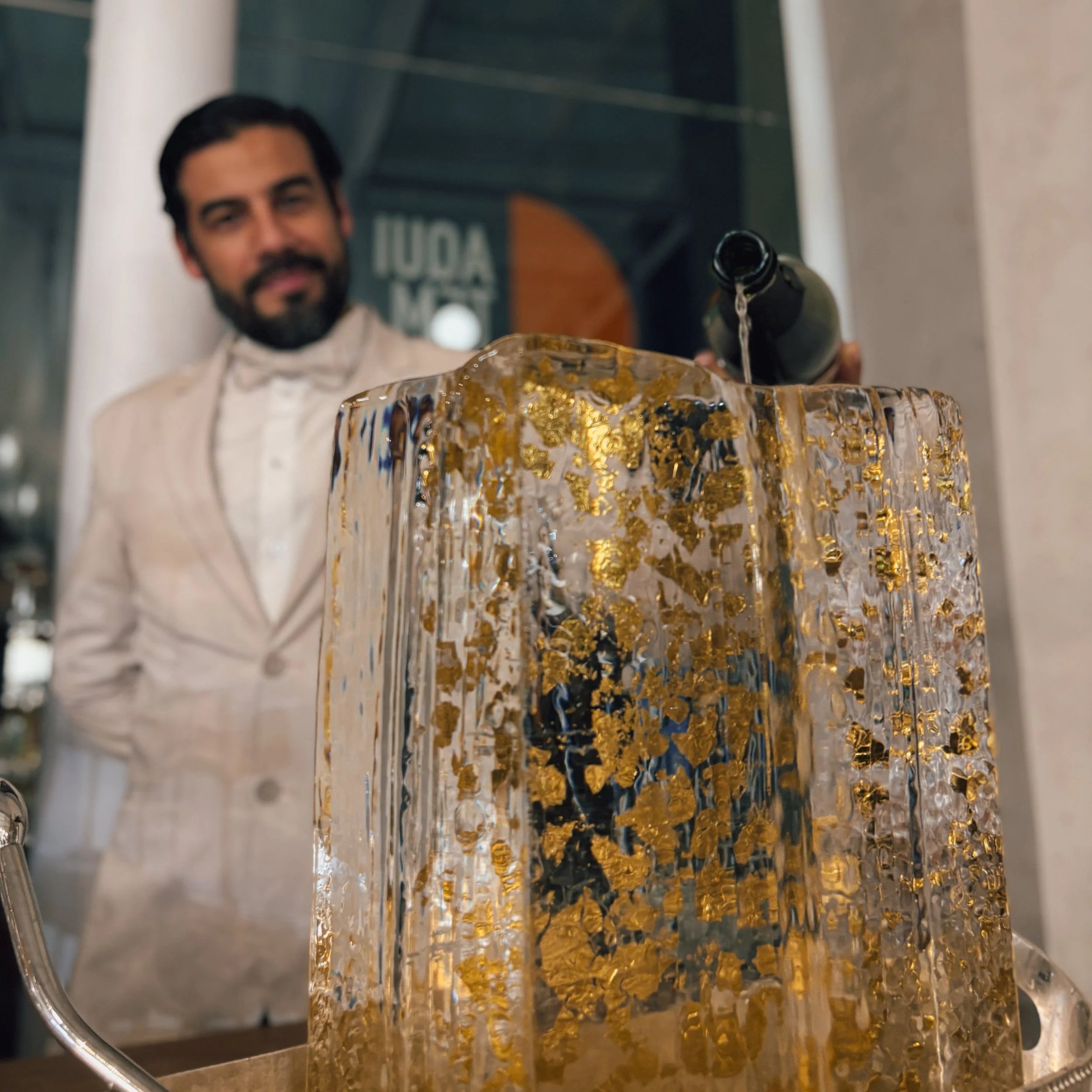 Homem servindo vinho em uma taça de vidro decorada com detalhes dourados