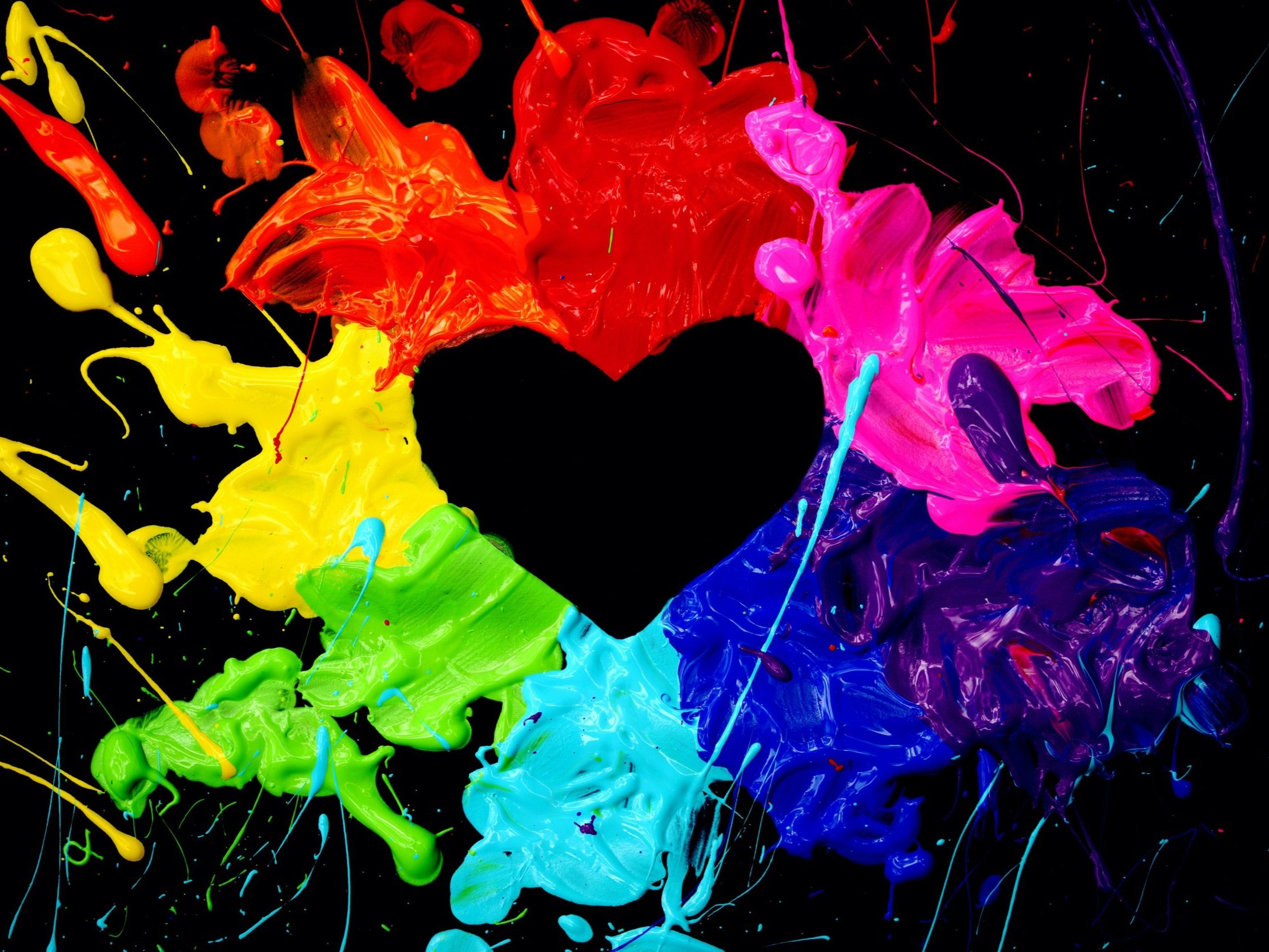 Black heart shape surrounded by colorful splashes of red, orange, pink, purple, blue, green, and yellow paint on a black background.