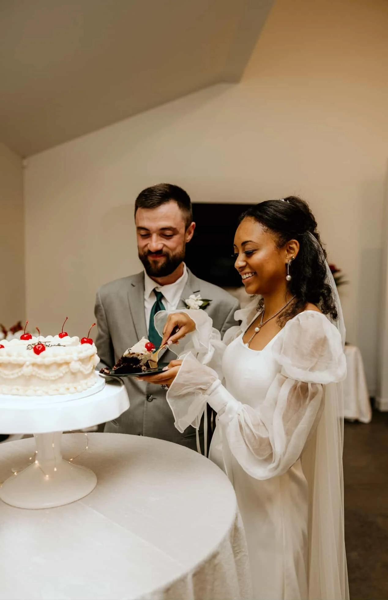 A bride and groom cutting and serving wedding cake at their wedding reception.