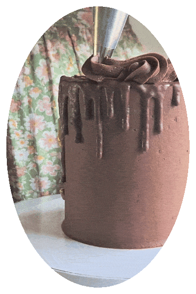 A chocolate cake with chocolate frosting, decorated with chocolate icing drizzle and topped with a piping bag.