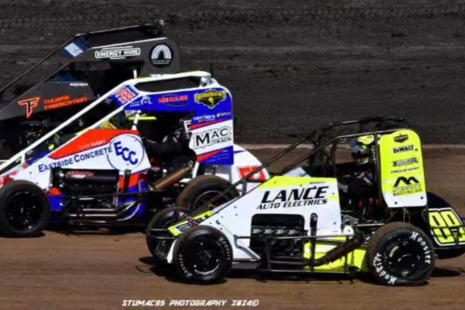 Three sprint cars racing on a dirt track, with one car in the foreground and two cars behind it.