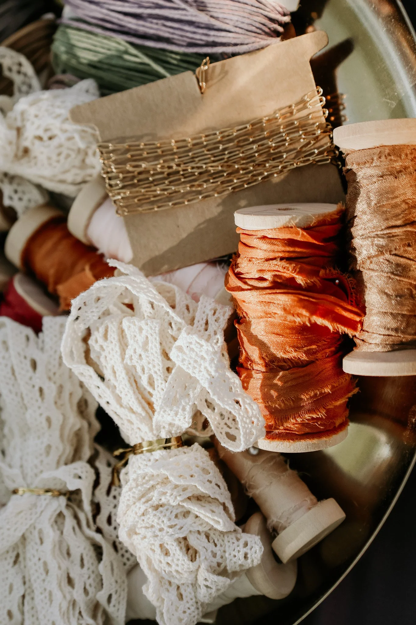 Various spools of fabric and lace trims in different colors and textures placed on a tray or surface.