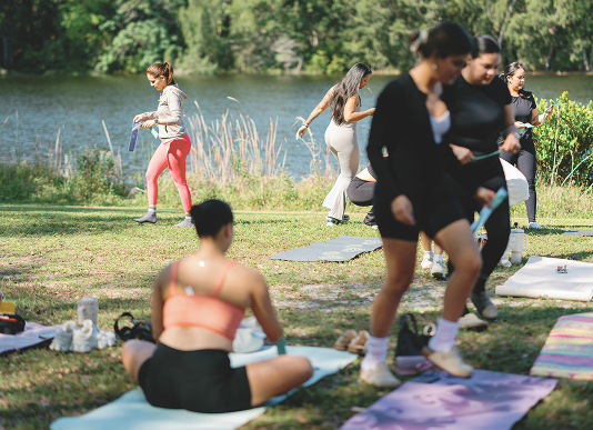 Women preparing for an outdoor Selah retreat practice by the water.
