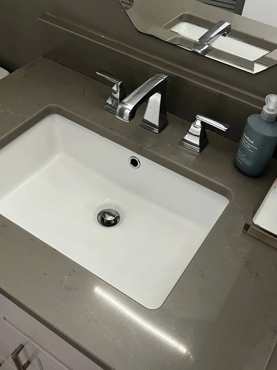 Bathroom sink with a chrome faucet, soap dispenser, and a mirror above the sink.