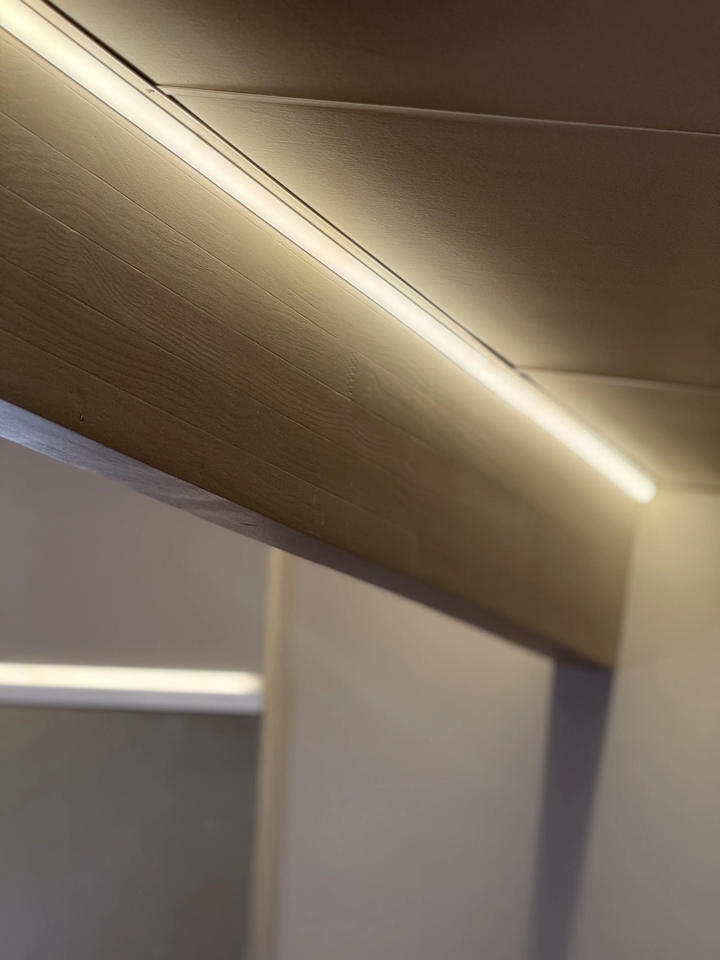 Close-up of a wooden desk or table with a built-in LED light strip underneath the surface.