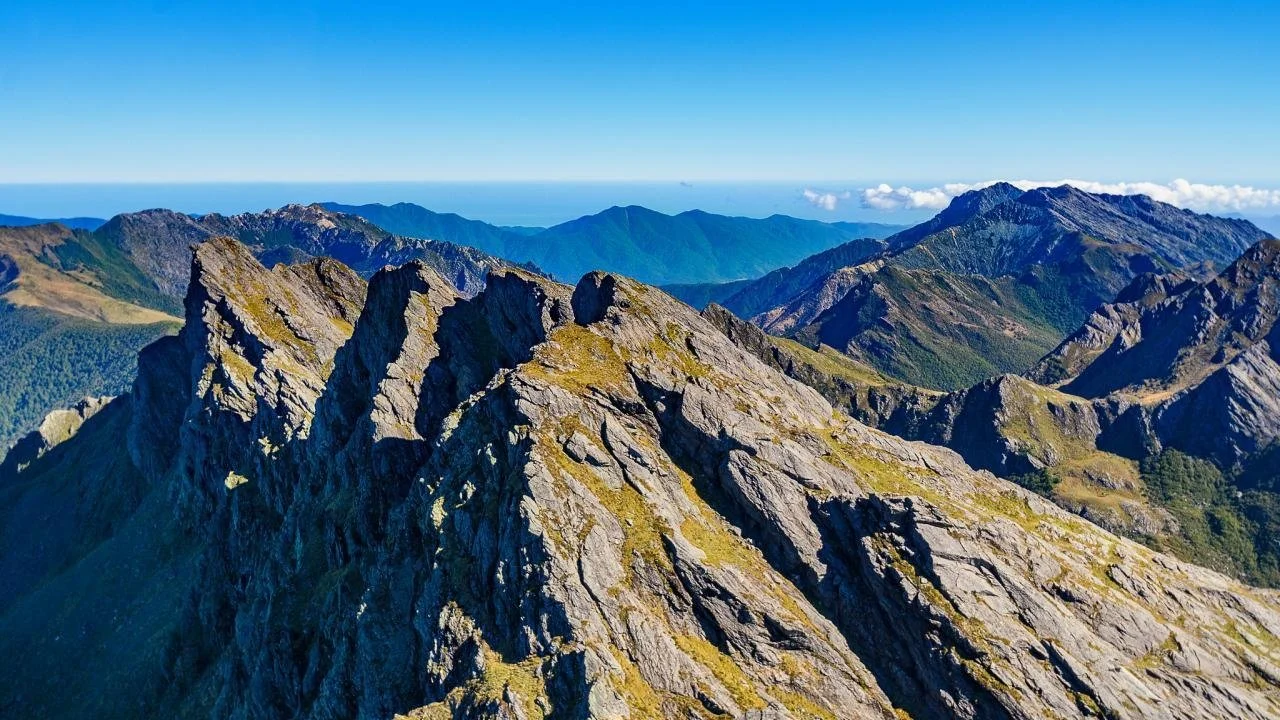Helicopter exploring the rugged alpine mountains and remote wilderness of Kahurangi National Park, Nelson Tasman, New Zealand.