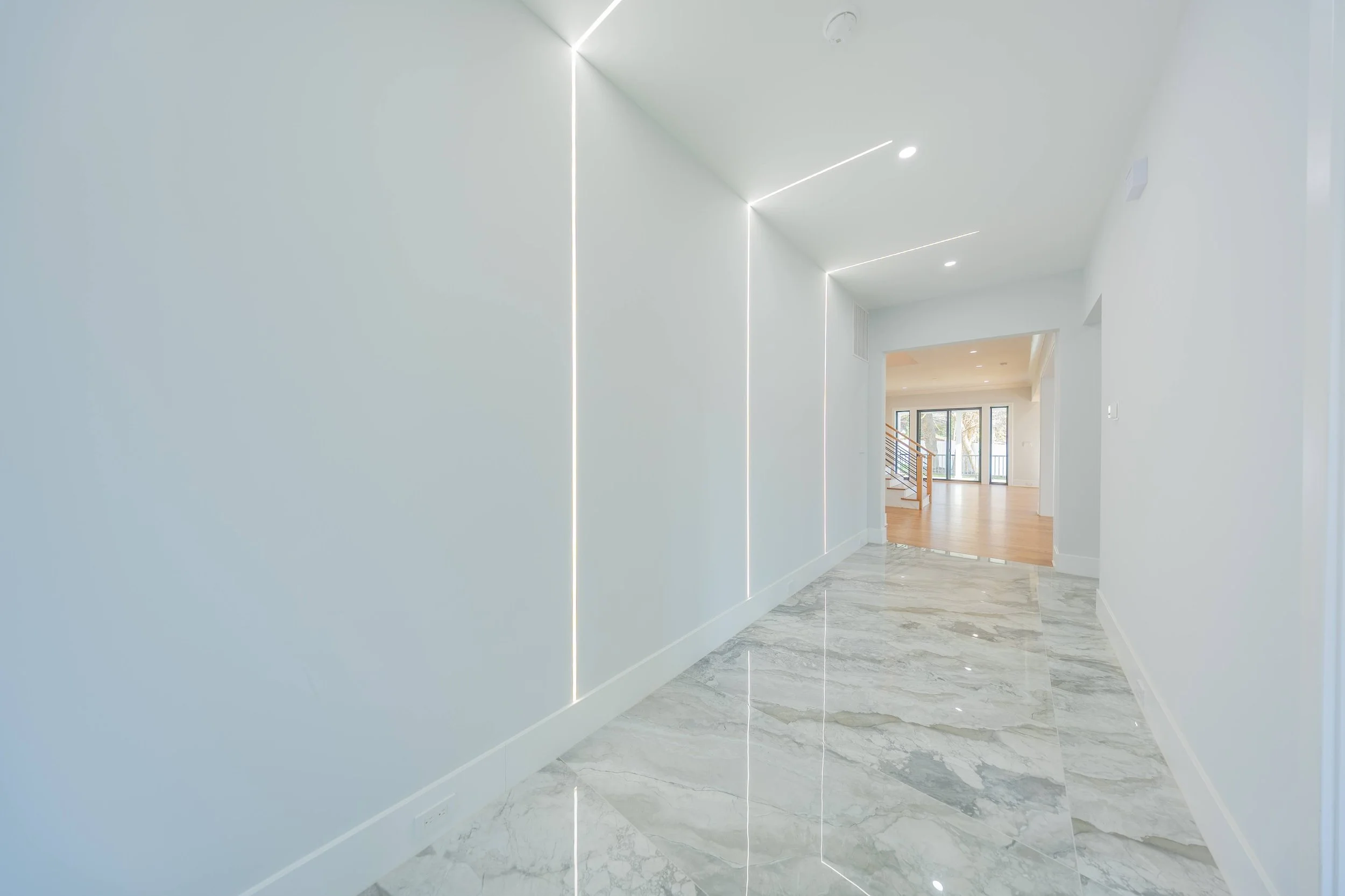 A white painted hallway with marble floor and led lights