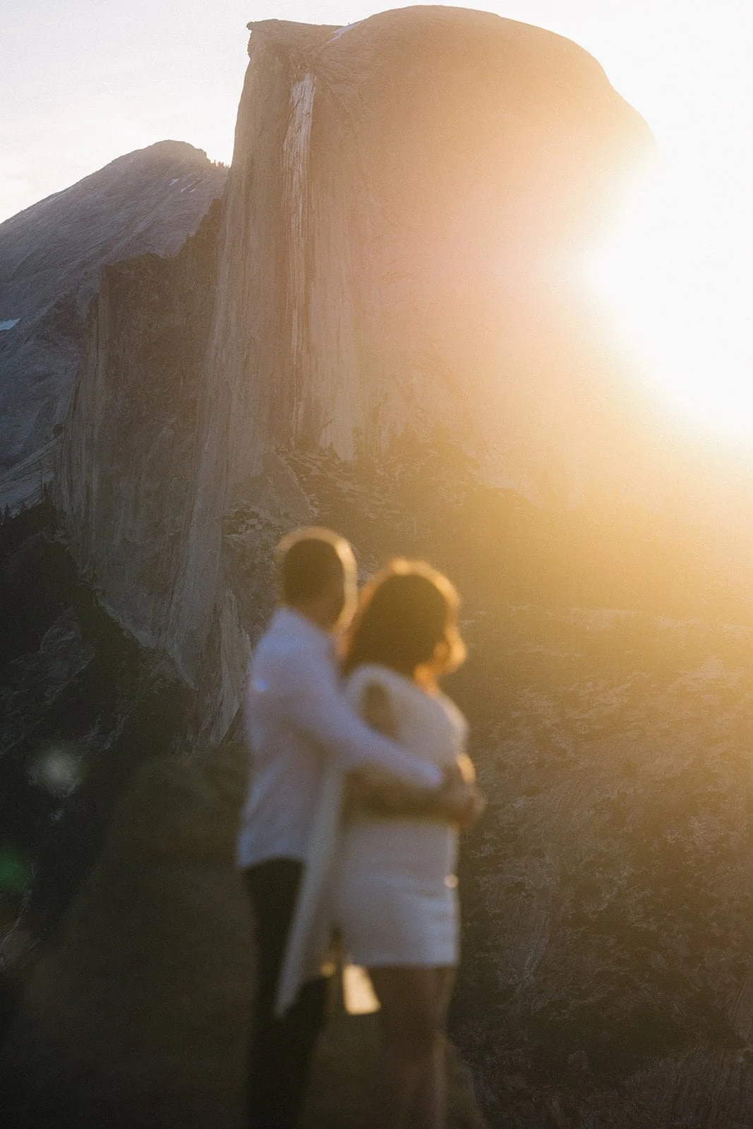 Couple silhouetted in front of Half Dome at Glacier Point in Yosemite during sunset