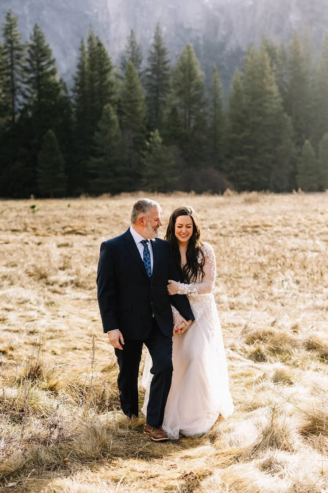 A bride and groom walking hand in hand through Catherdral Meadow in Yosemite
