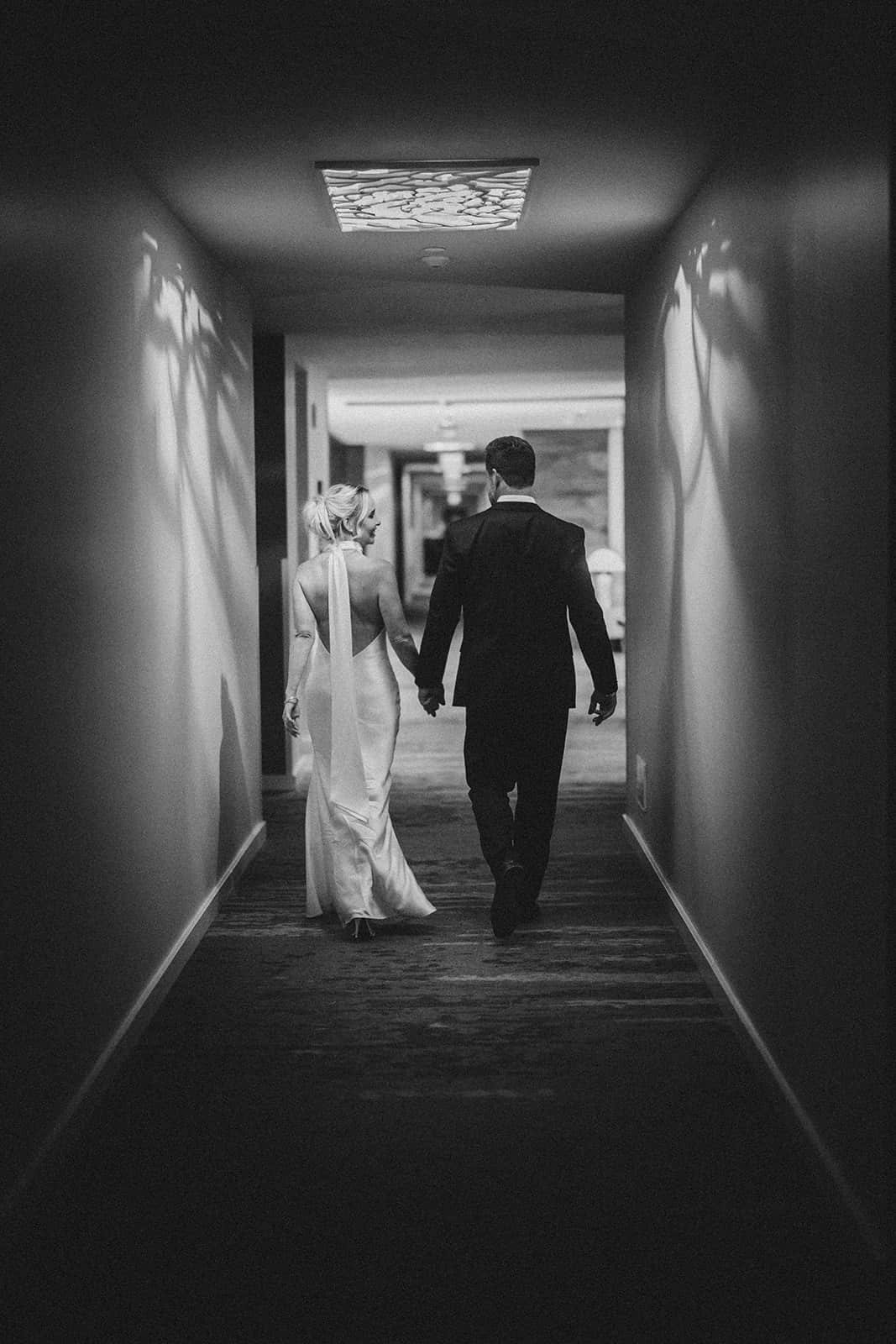 Bride and groom walking down hotel hallway.jpg