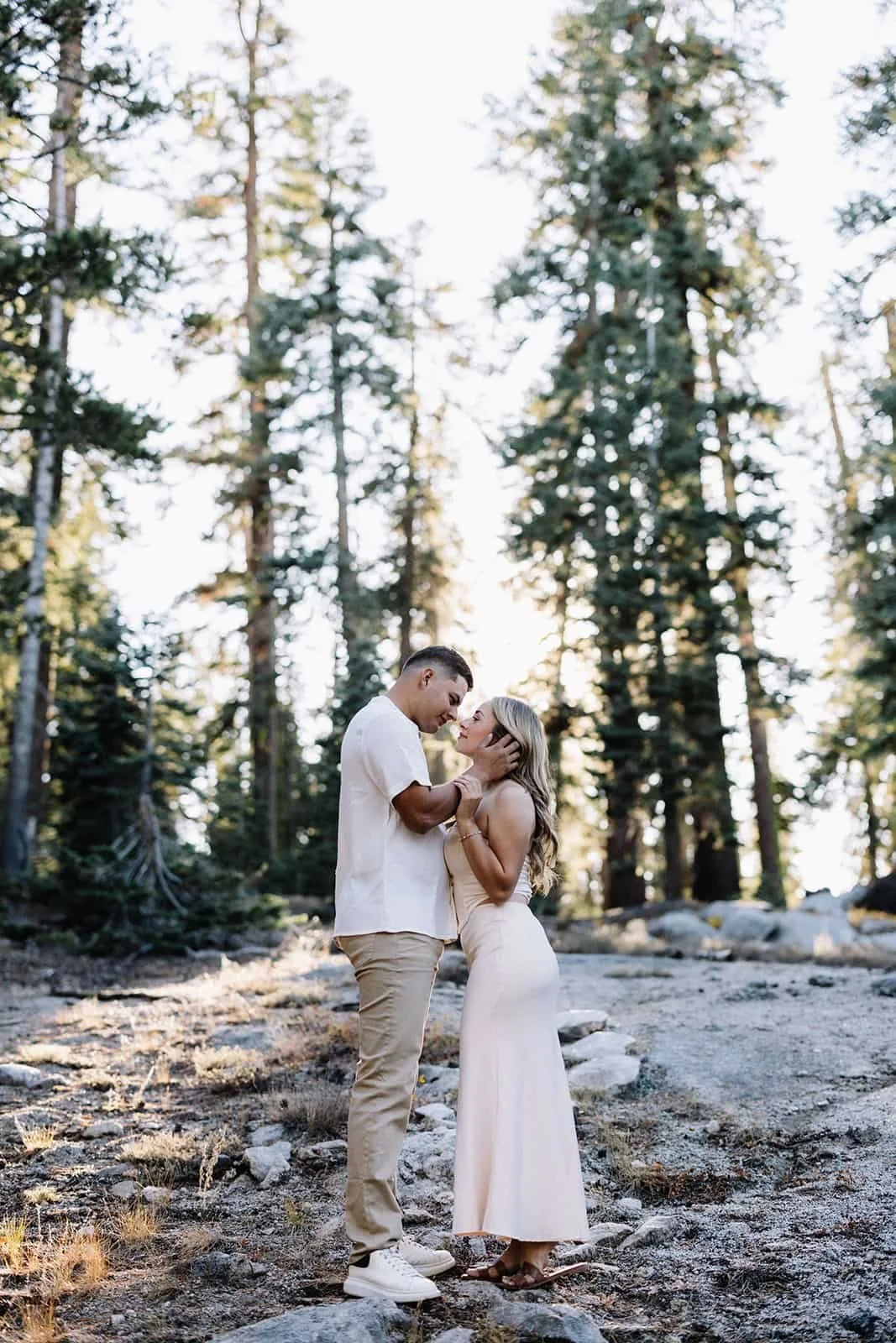 Couple standing close together in the forest at Taft Point in Yosemite, surrounded by tall trees and natural scenery