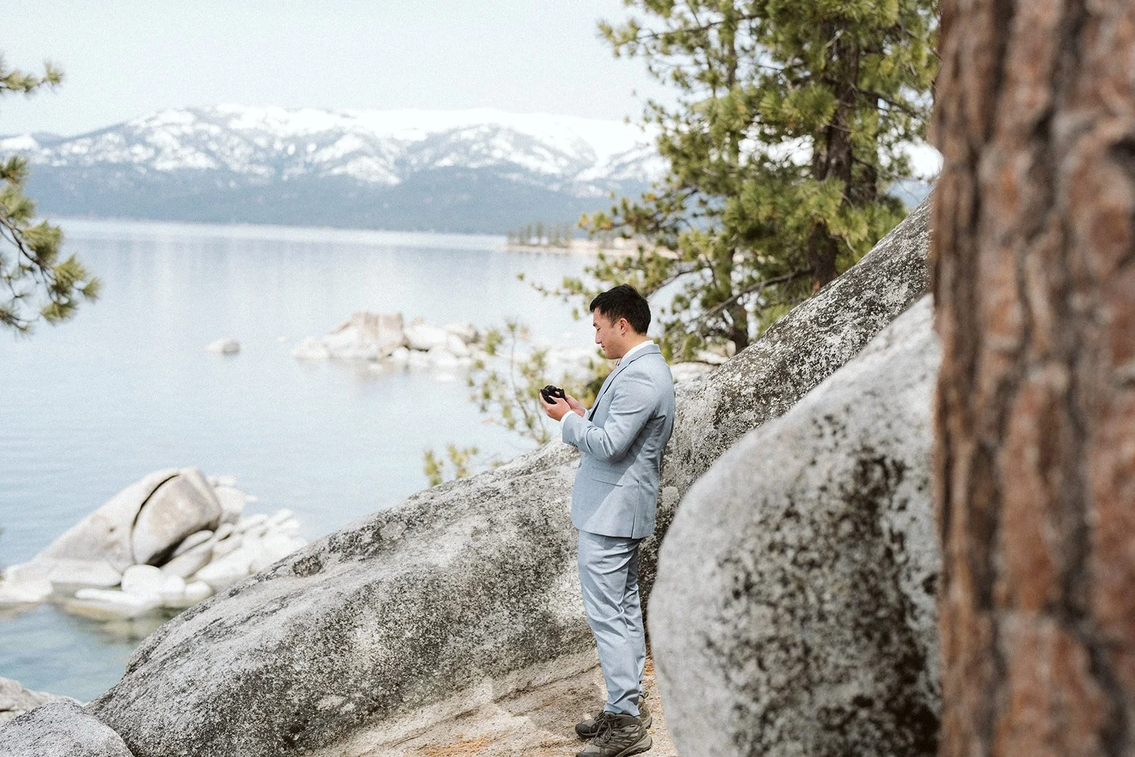 Groom getting ready on Lake Tahoe shoreline rocks before elopement ceremony — AJ Photography