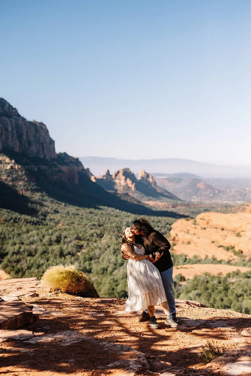 A couple sharing a kiss on a rocky ledge in Sedona AZ