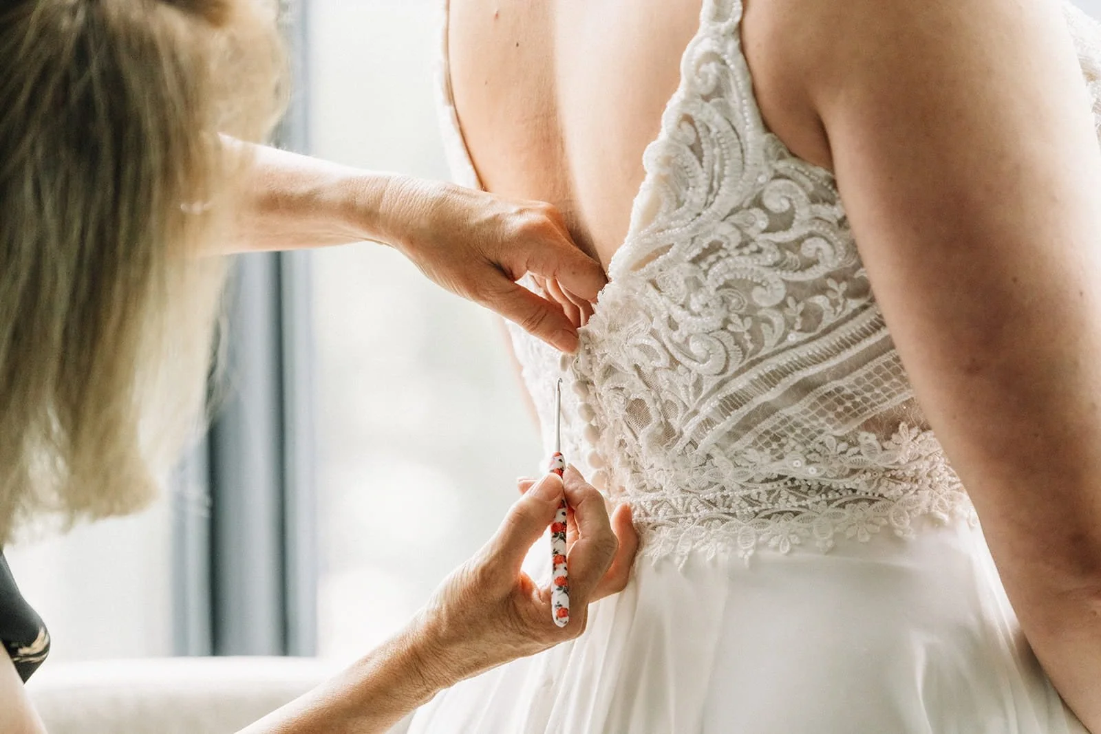 close up of bride dress getting button up.jpg