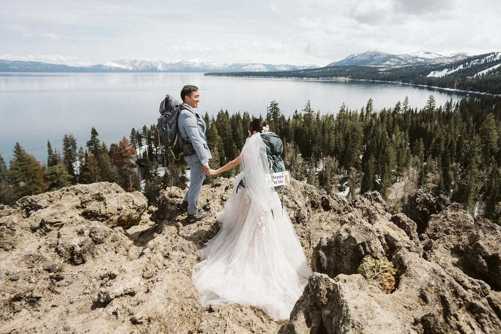 Bride with Happy Wife sign and groom in hiking gear at Eagle Rock, Lake Tahoe elopement — AJ Photography