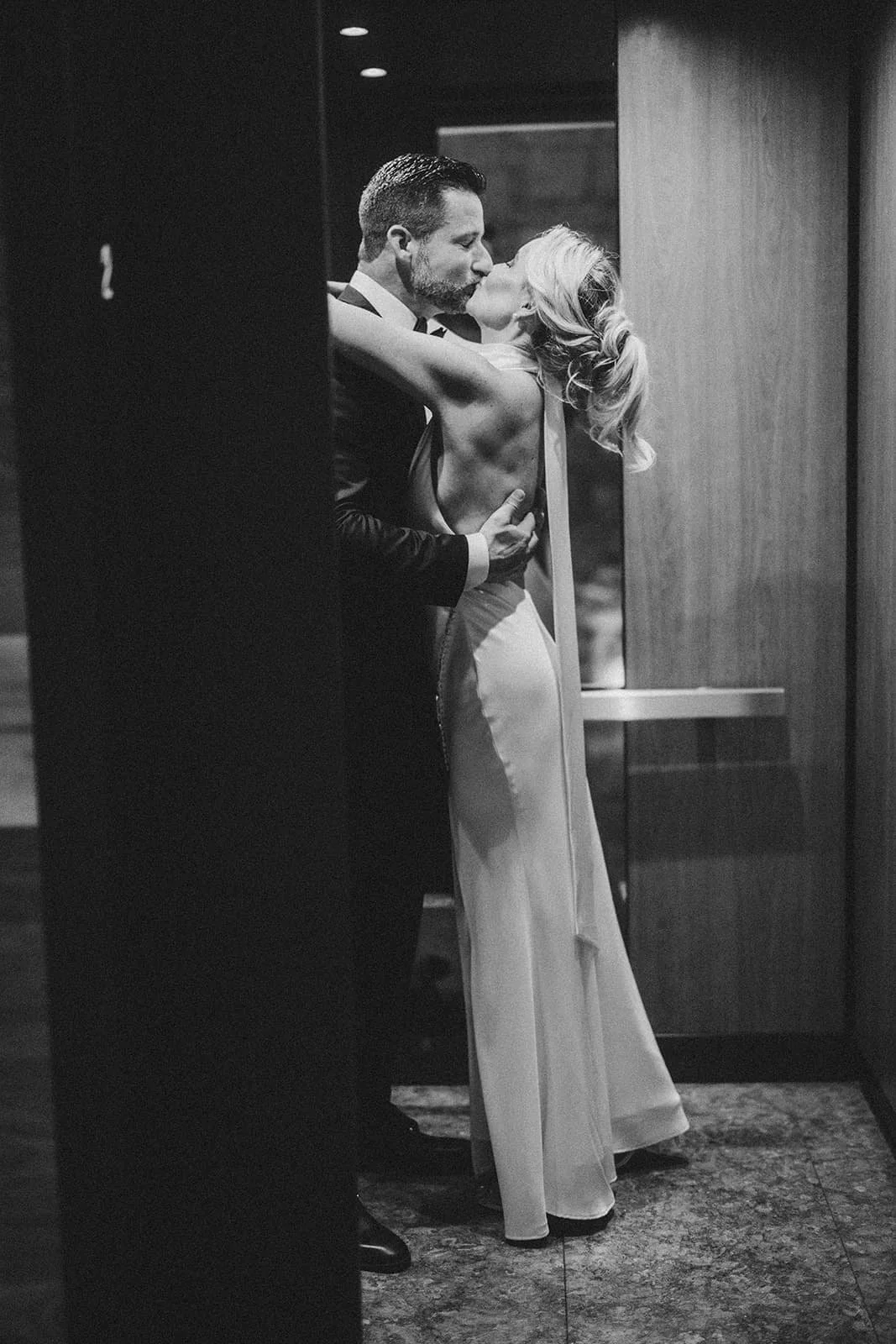 bride and groom kissing in elevator in hotel.jpg