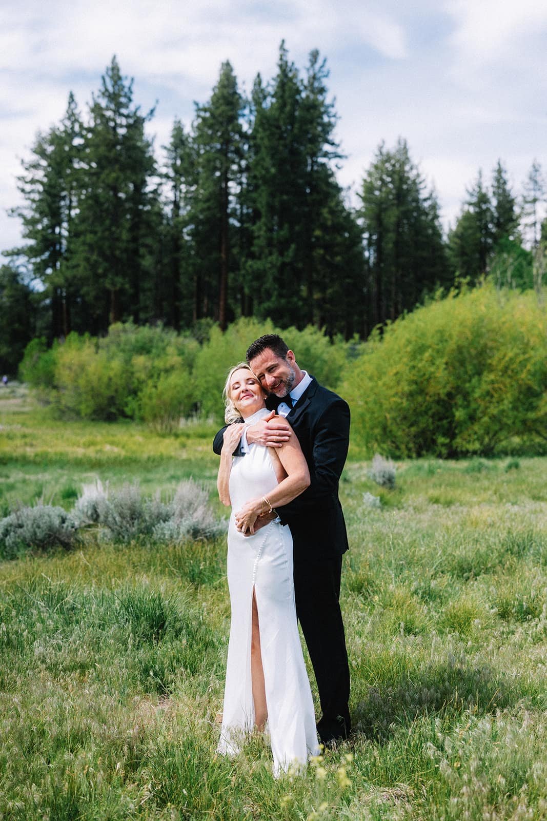 Close-up of the bride and groom embracing among pine trees.jpg