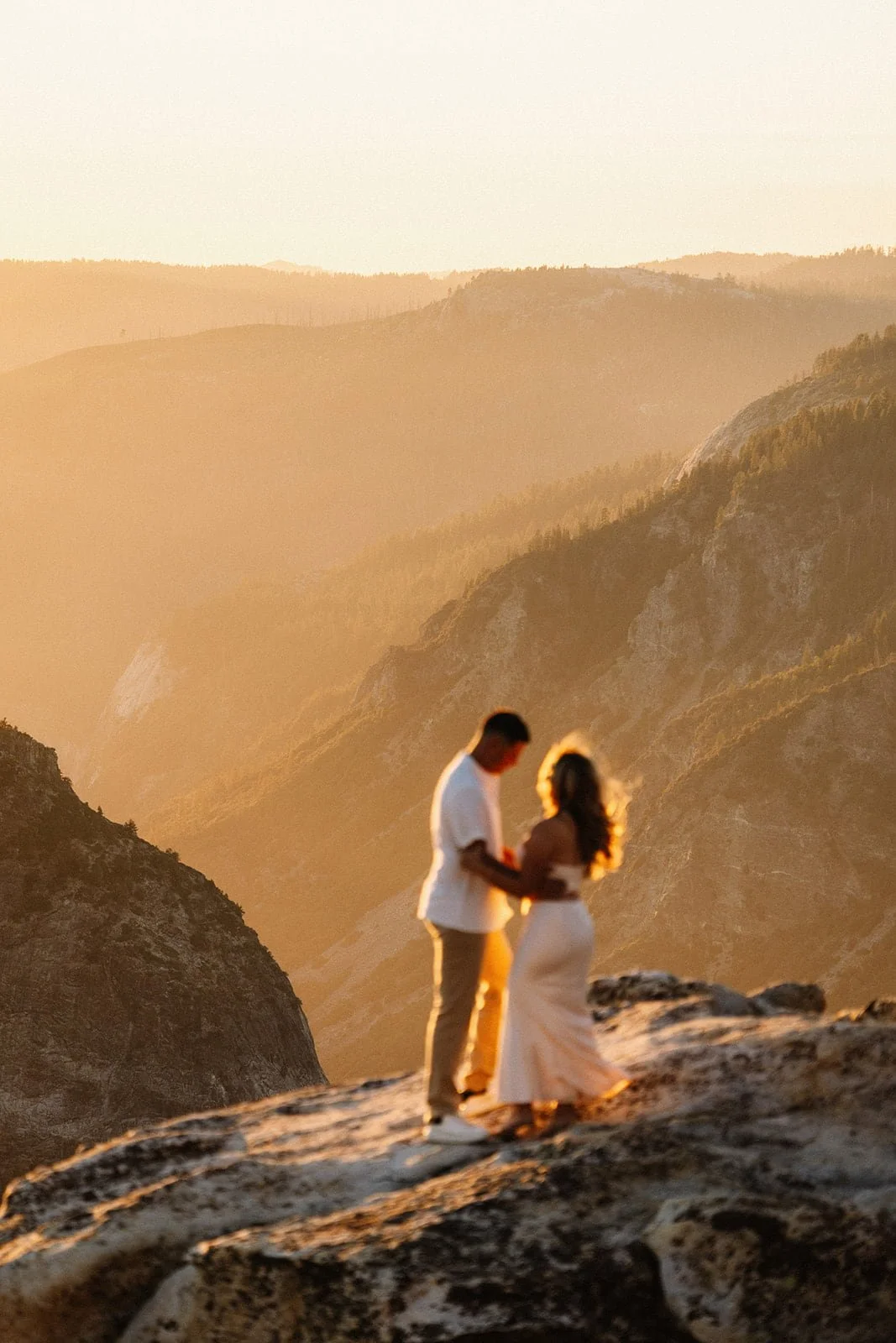 Couple embracing on the cliffs of Taft Point in Yosemite at sunset during their engagement session