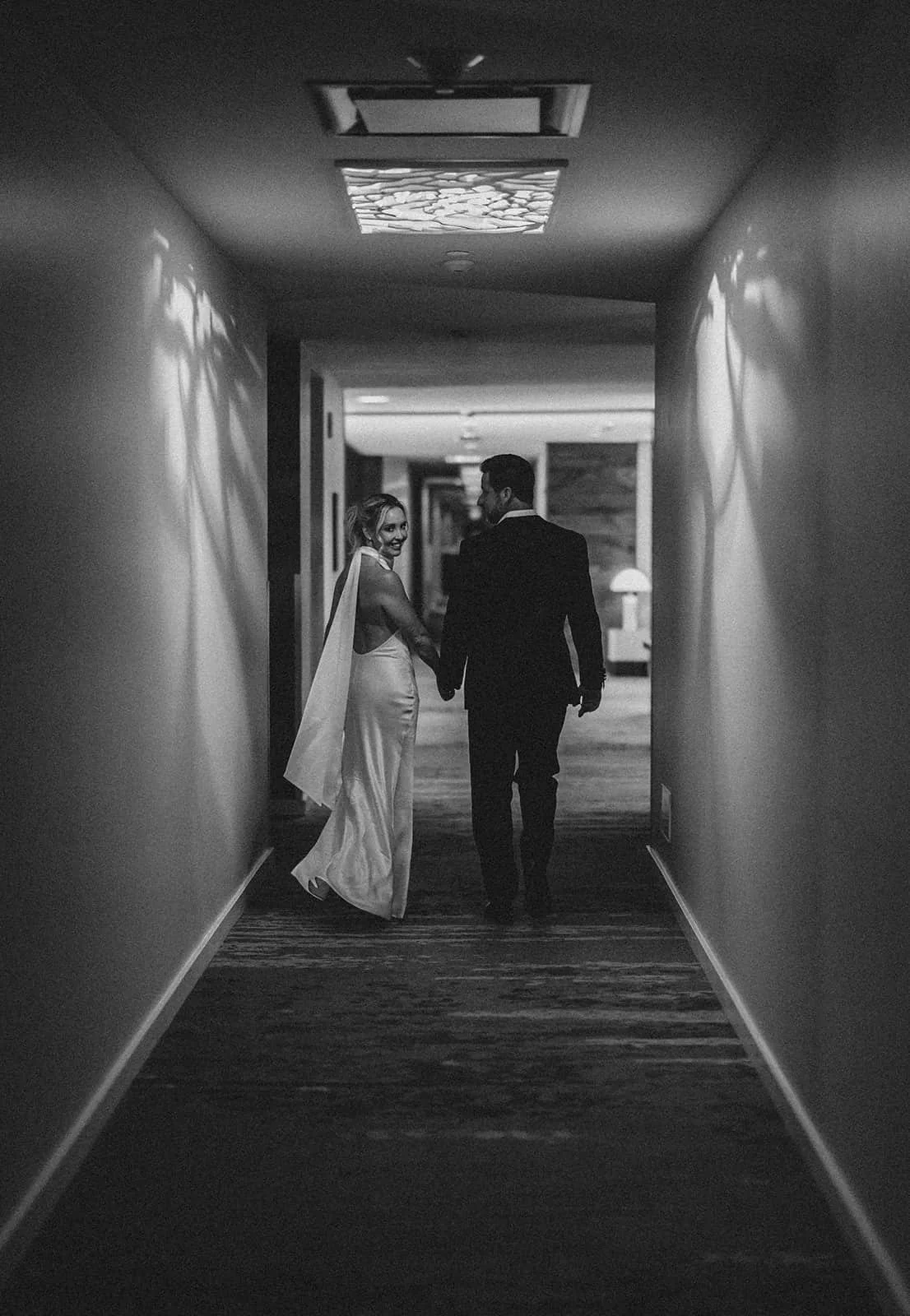 bride looking over her shoulder walking through hotel hallway.jpg