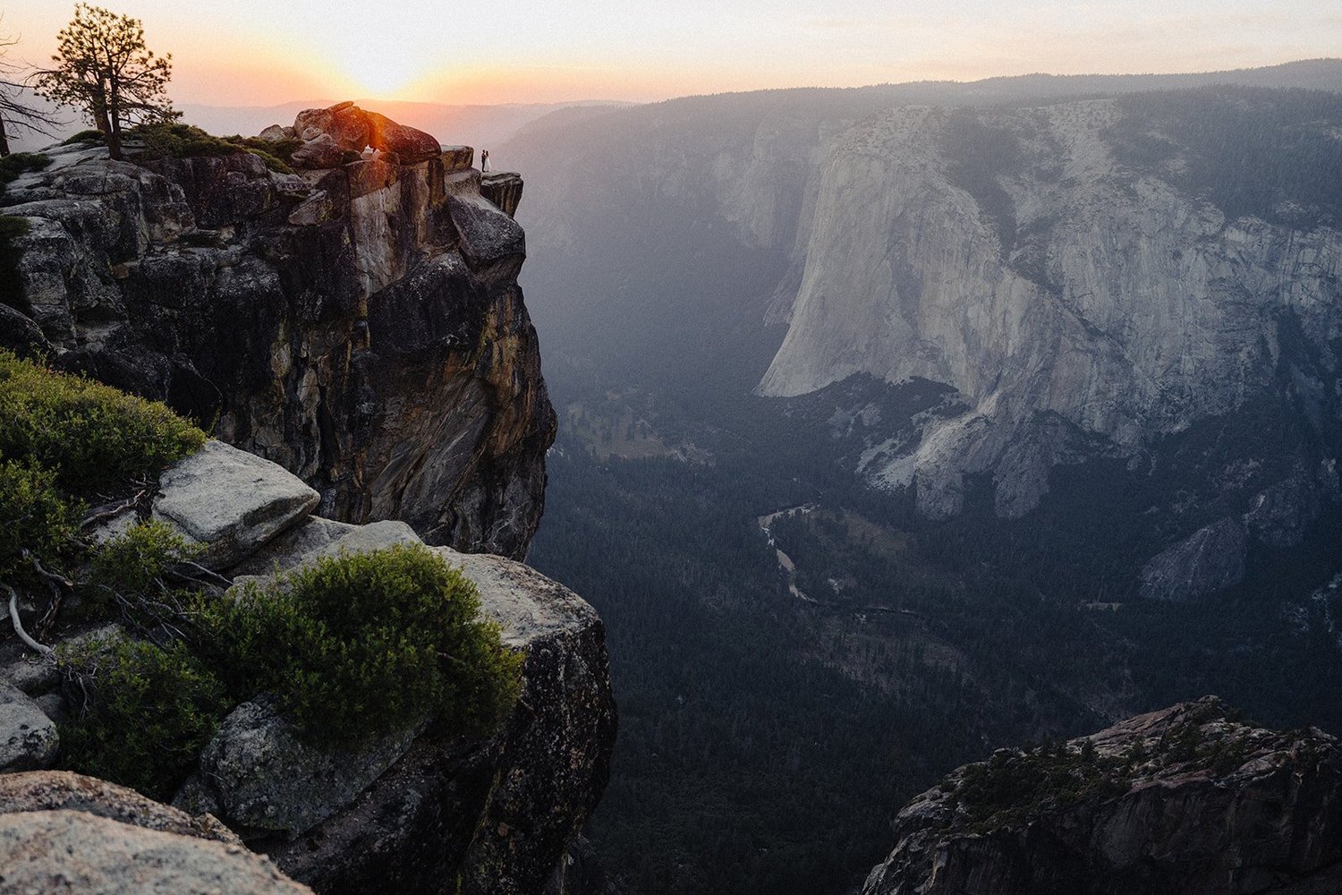 Taft Point sunset elopement — couple on the cliff edge at Yosemite with El Capitan and the valley below, photographed by AJ Photography NV