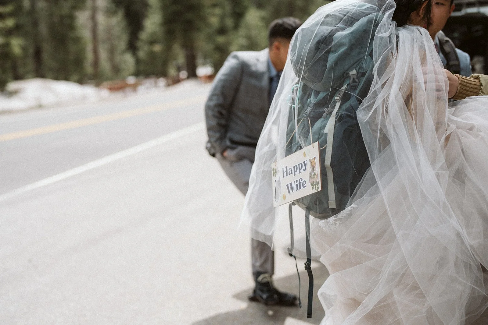 Bride with veil and Happy Wife backpack sign, adventure elopement at Lake Tahoe — AJ Photography