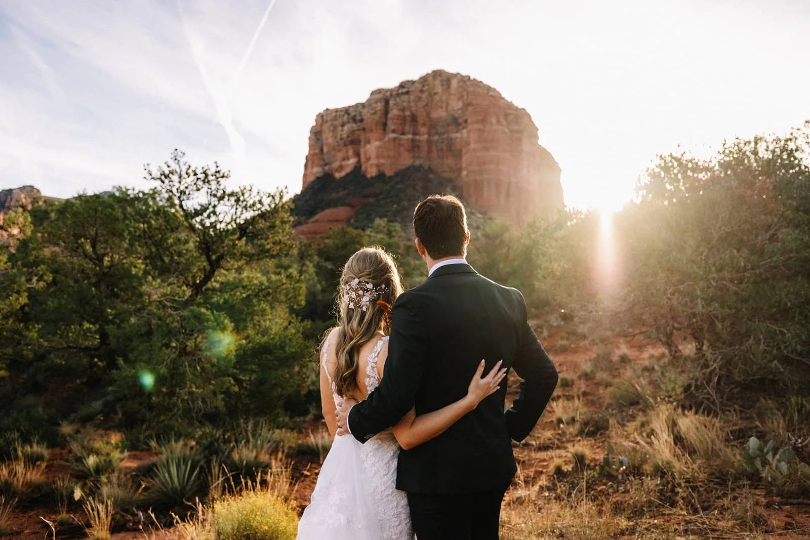 Bride and groom embracing at sunset beside a Bell rock formation during their Sedona elopement