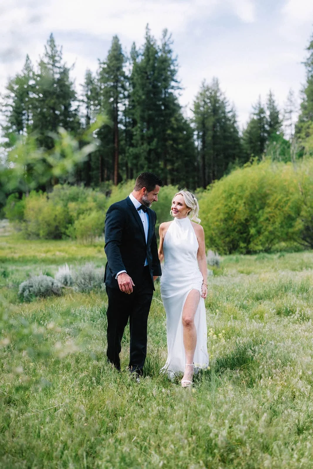 Bride and groom walking together in an open field, holding hands.jpg