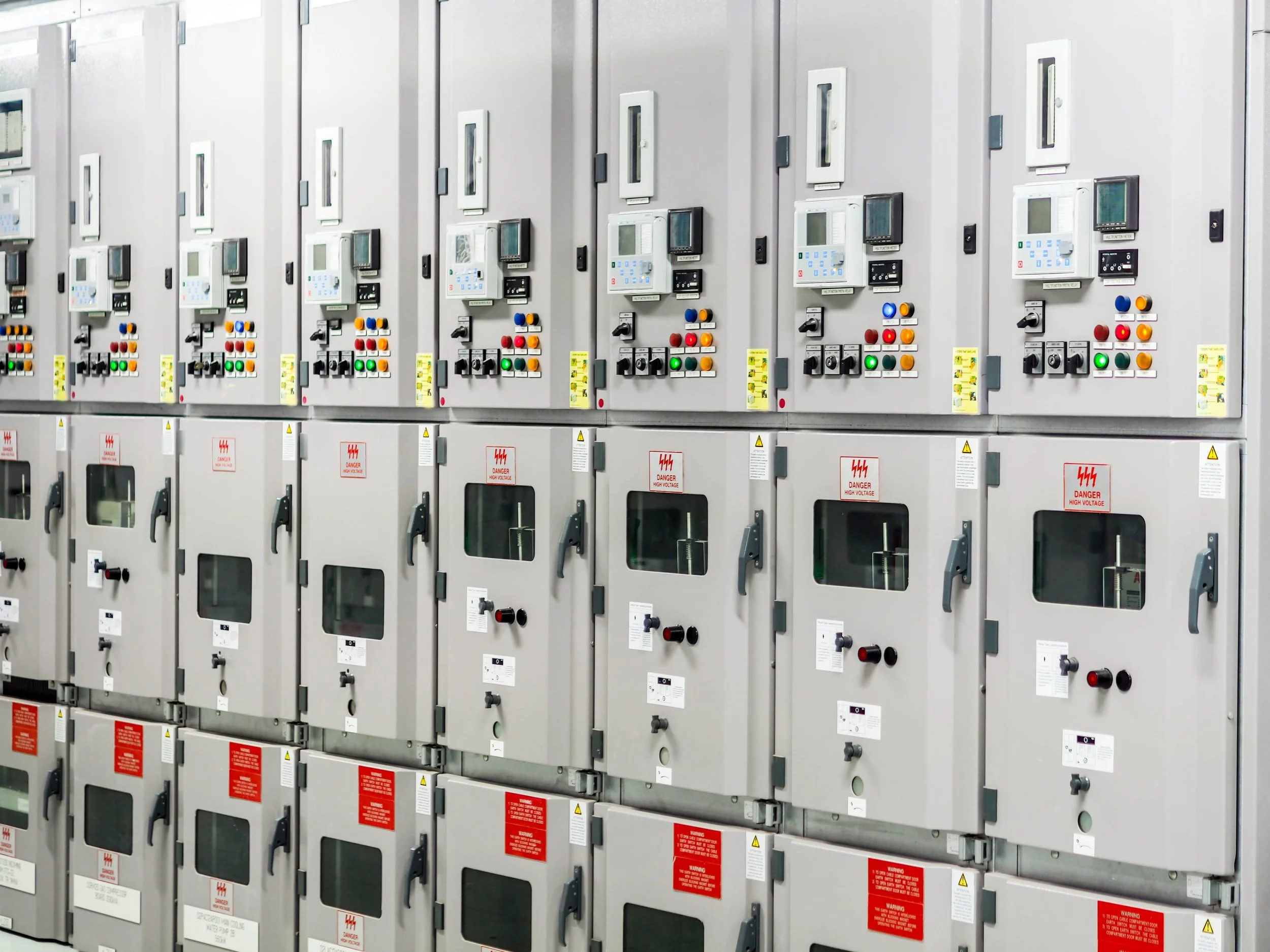 Electric control panels and switchgear cabinets in an industrial setting, with various buttons, switches, and digital displays.