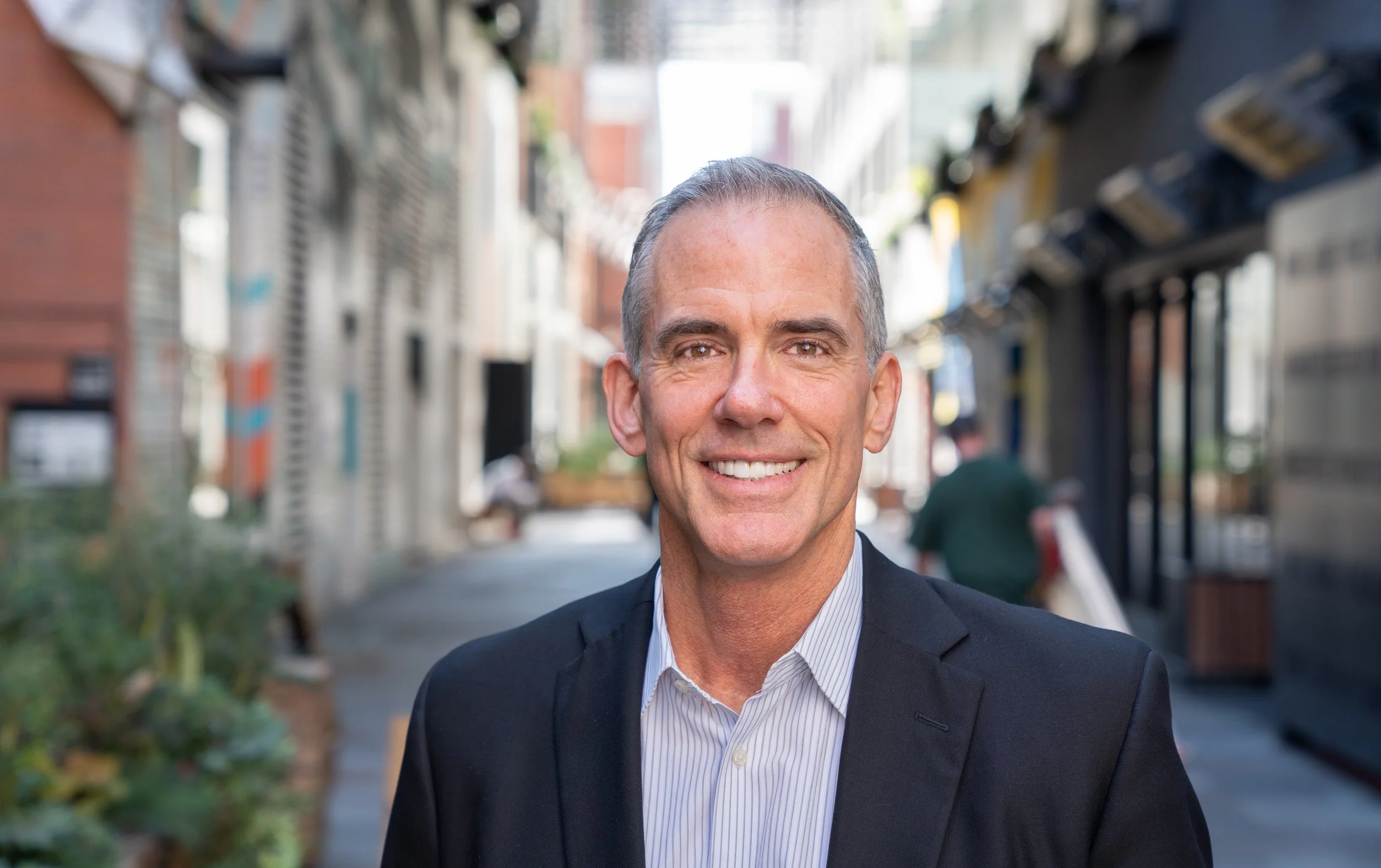 Photo of Ray Pittman, Jr. President of PDG wearing a suit and tie with an urban alleyway in the background.