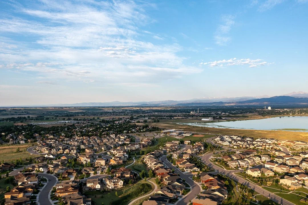 Aerial view of Centerra land development with residential houses, winding streets, and a large lake.