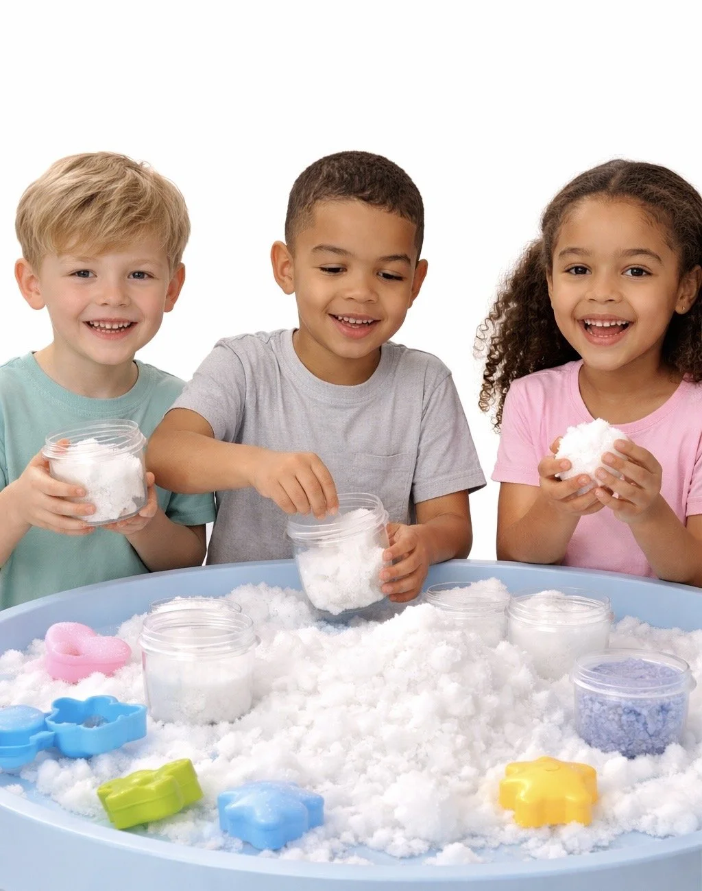 Three children playing with fake snow, holding containers of snow and smiling, at a sensory play table with colorful sand molds.