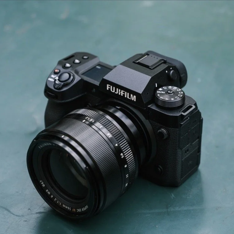 Fujifilm digital camera with a large zoom lens on a teal surface