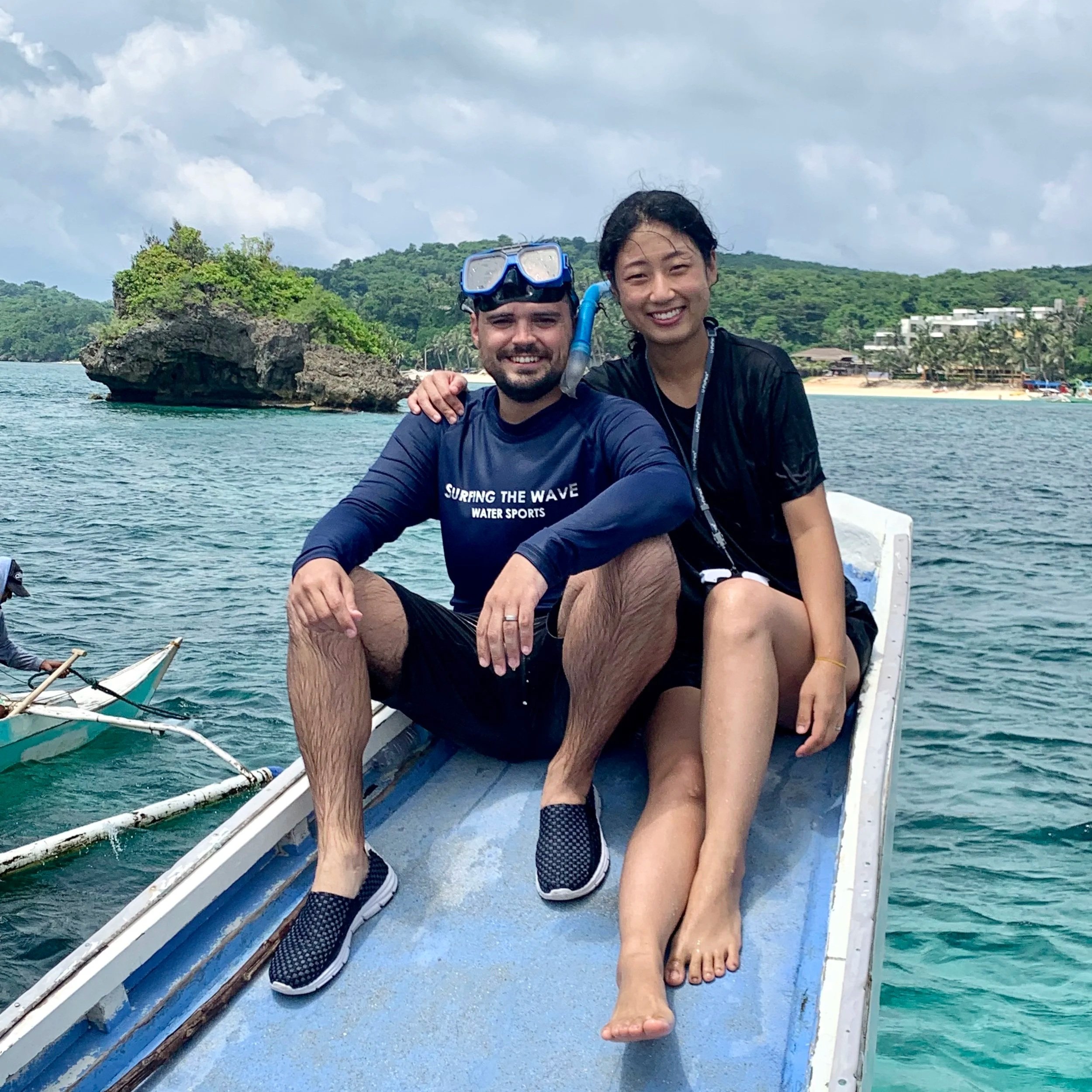 Kevin Miller and wife on a traditional long boat after snorkeling, turquoise waters and green islands in background, Boracay, Philippines