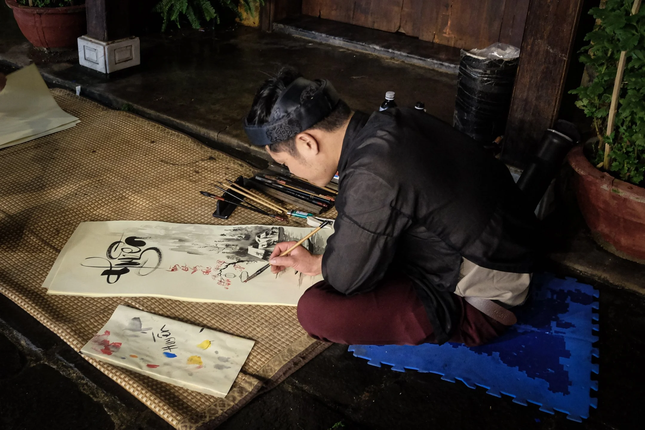 Local artisan doing traditional Vietnamese painting on paper scroll in Hoi An's Old Town, Vietnam