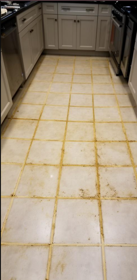 Kitchen floor with large white tiles and yellow grout lines.