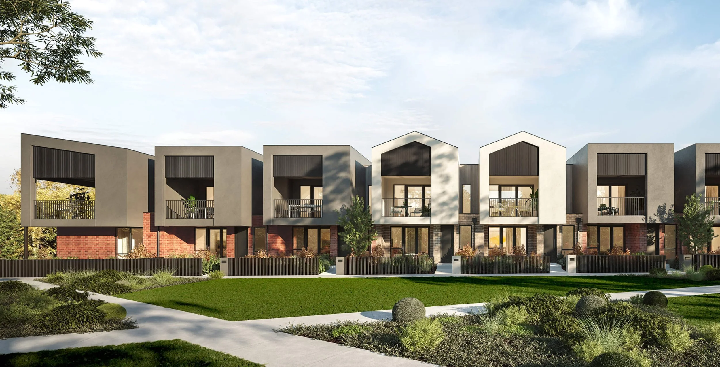 A modern residential building with multiple units, featuring a combination of brick, concrete, and black panel facades. The building has open-air balconies on the upper level, trees and landscaped greenery in front, and a well-maintained grass lawn with walkways.