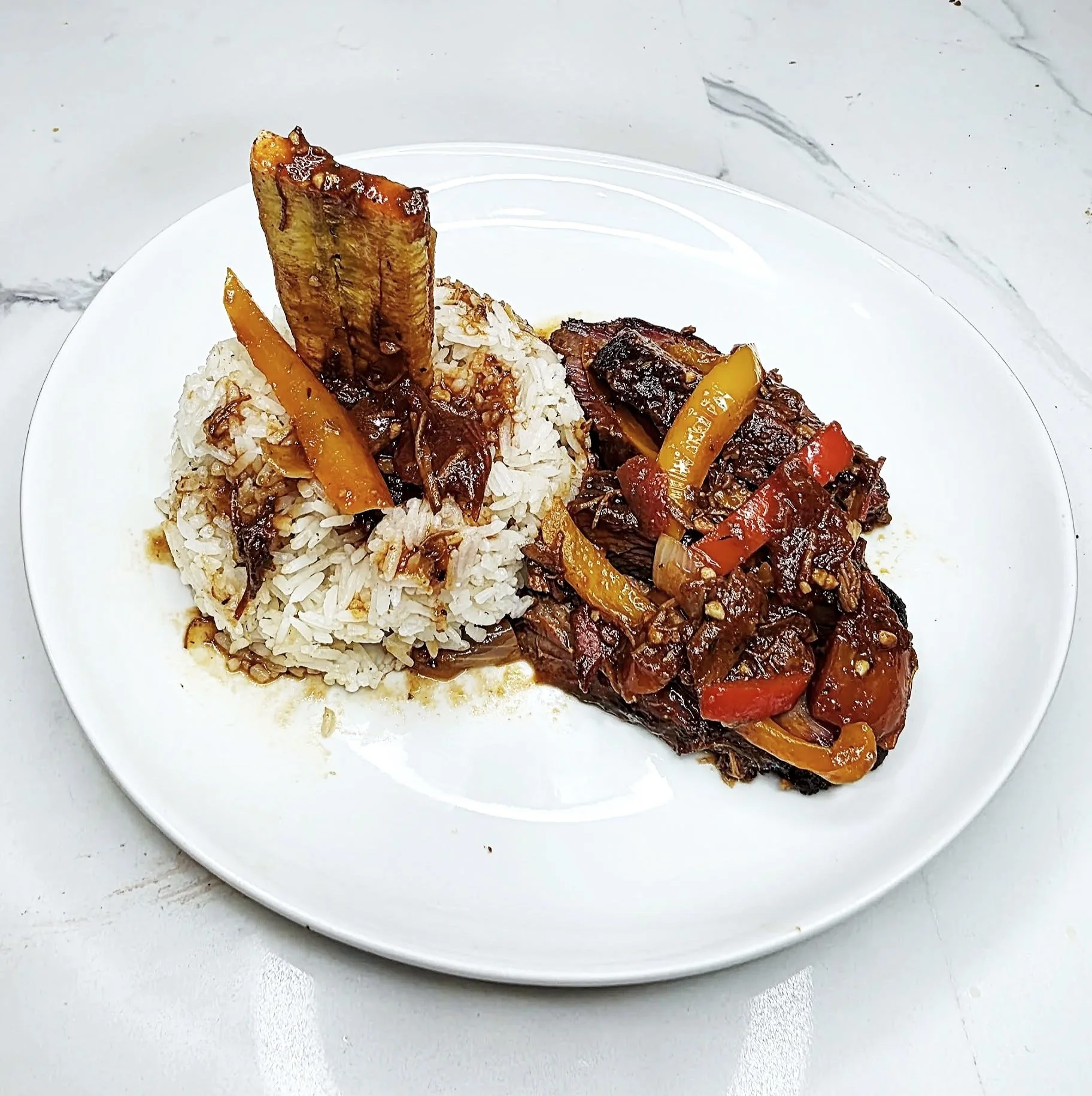 Plate with rice and beef stew or similar dish with vegetables.