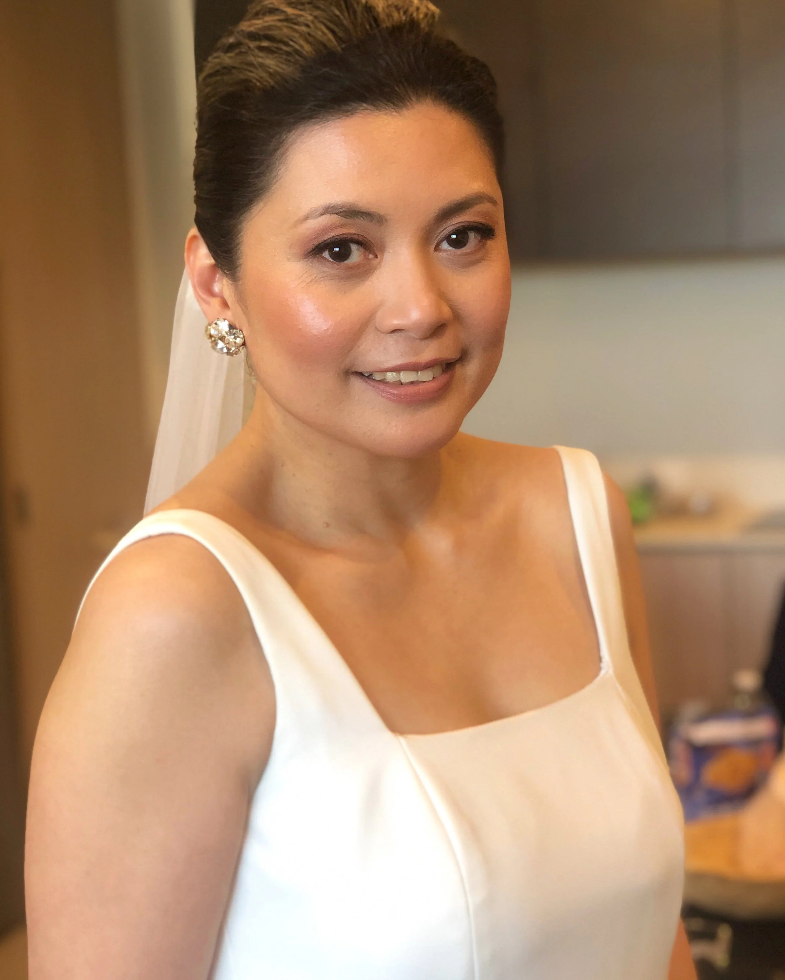 A bride in soft hair and makeup being photographed in a hotel room in South Yarra in Melbourne on her wedding day.