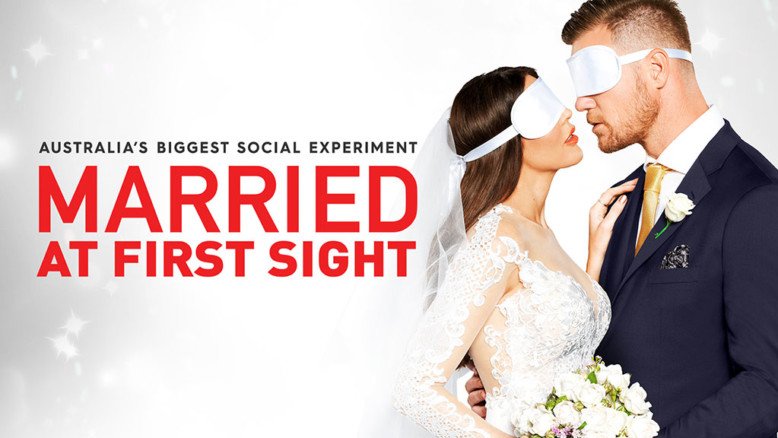 A bride and groom in wedding attire wearing blindfolds, standing close together with noses touching, holding a bouquet of flowers, for a promotional poster titled 'Married at First Sight' for Australia's biggest social experiment.