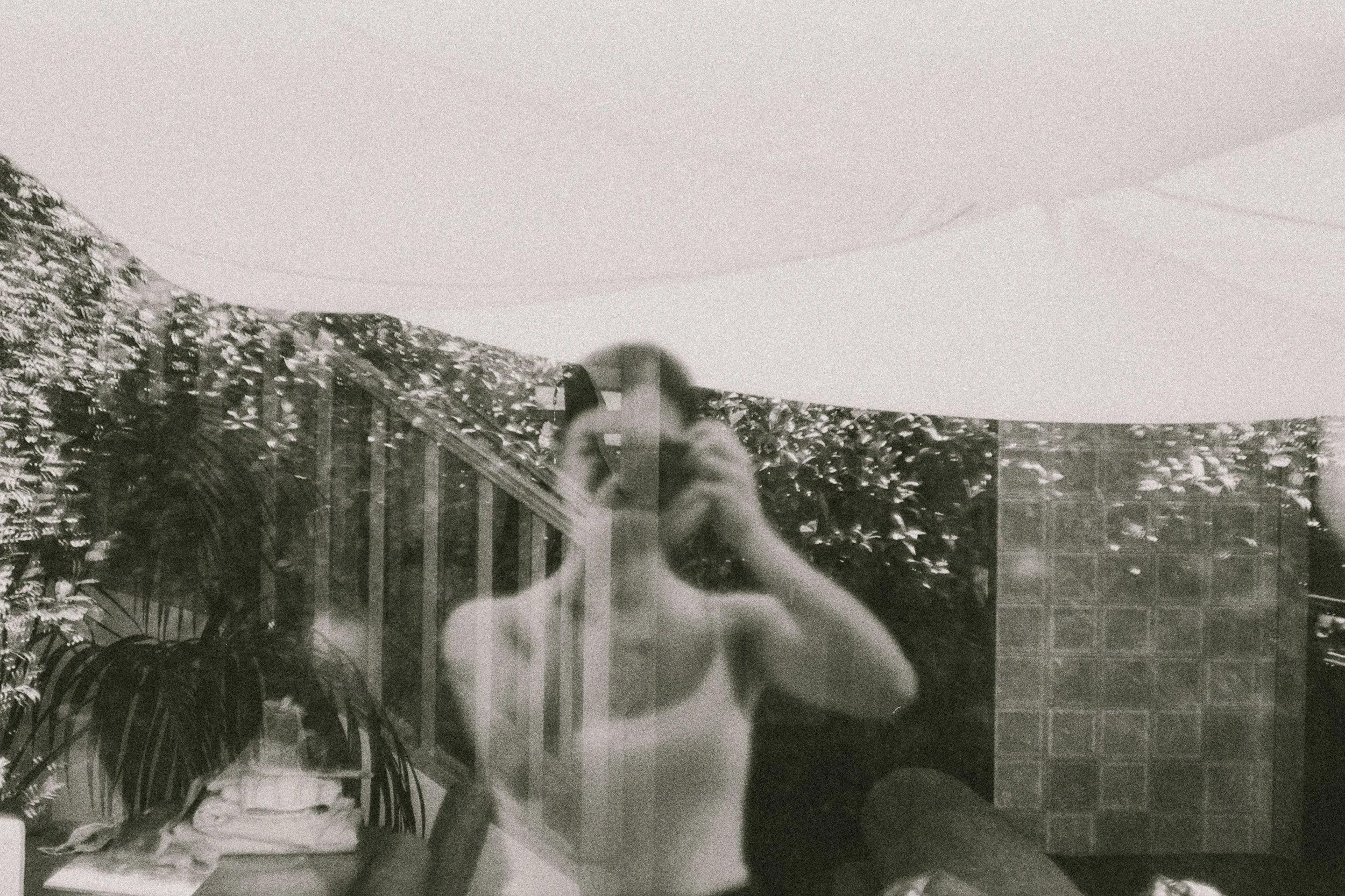 someone taking a photo of themselves reflection double exposure with mountains in the back