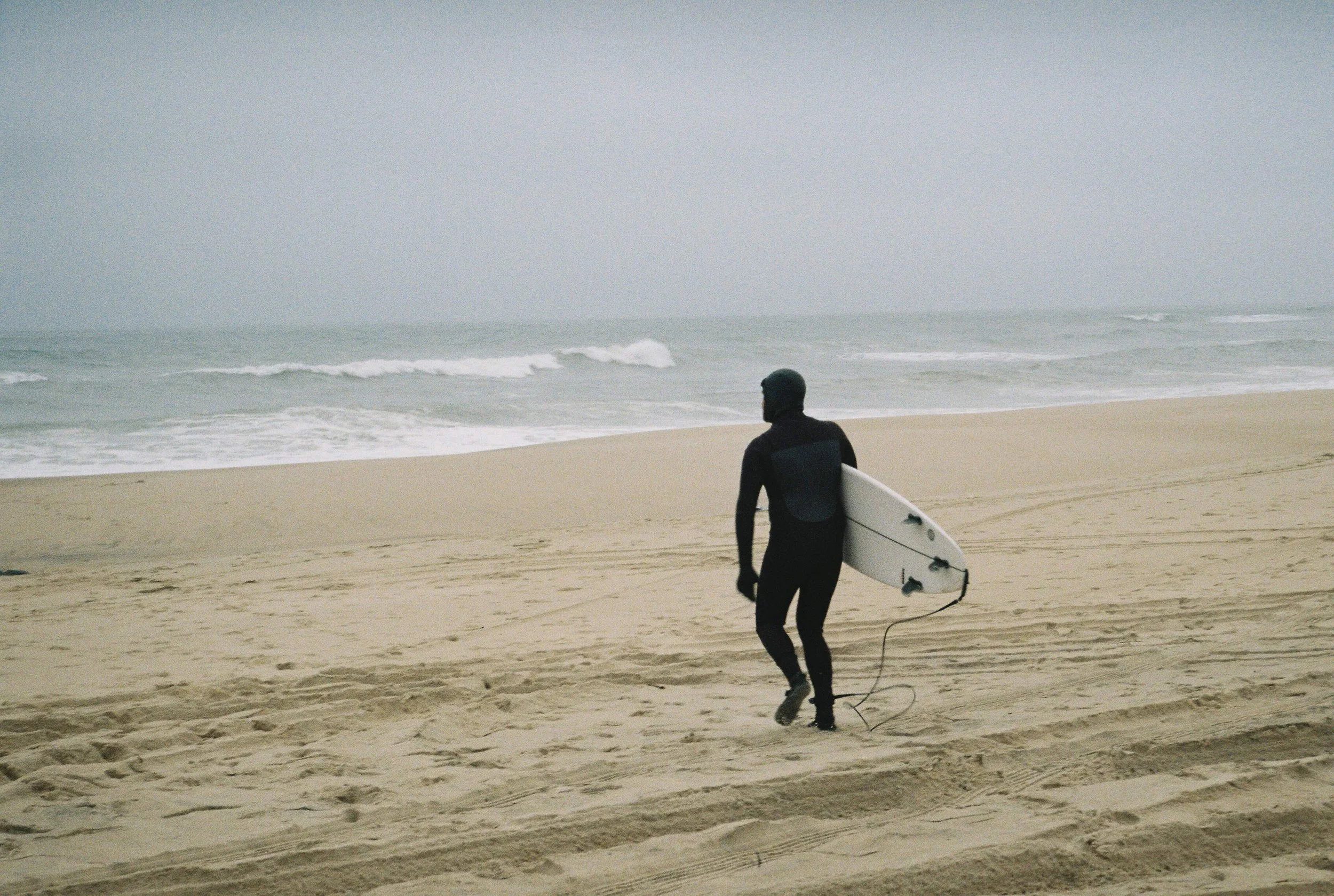 surfing running into the ocean in a wetsuit at georgica beach