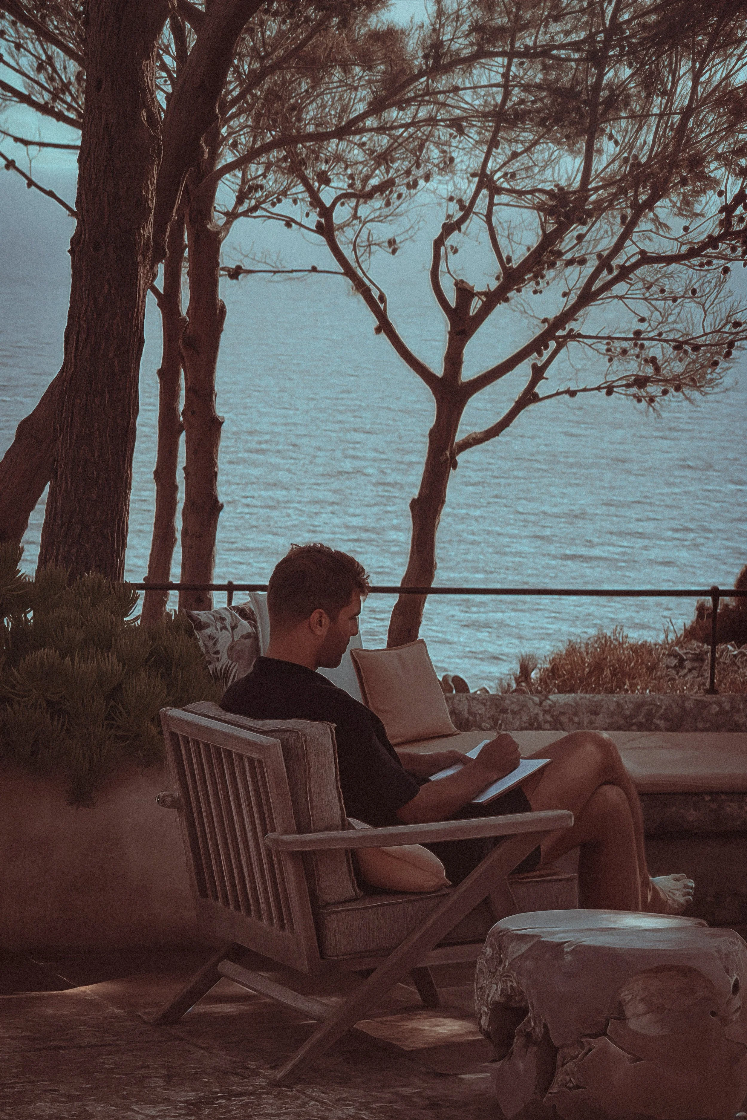 Thomas Dohm writing by the sea at dusk in Puglia, Italy, 2025