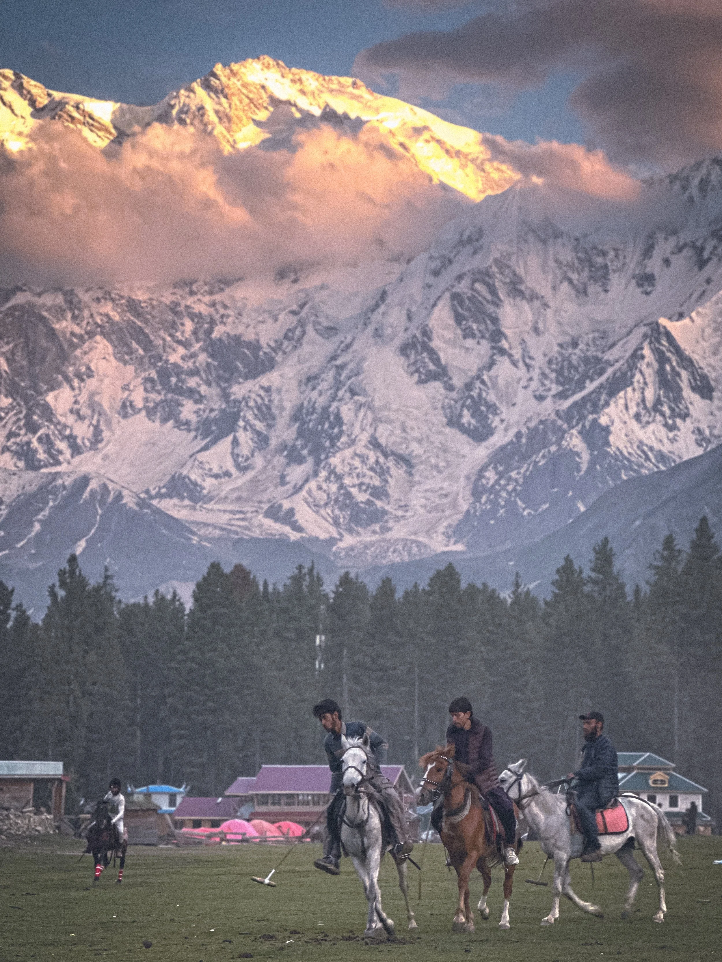 Polo players on horseback at golden hour with the Karakoram range in Fairy Meadows, Pakistan. Photography by Thomas Dohm.